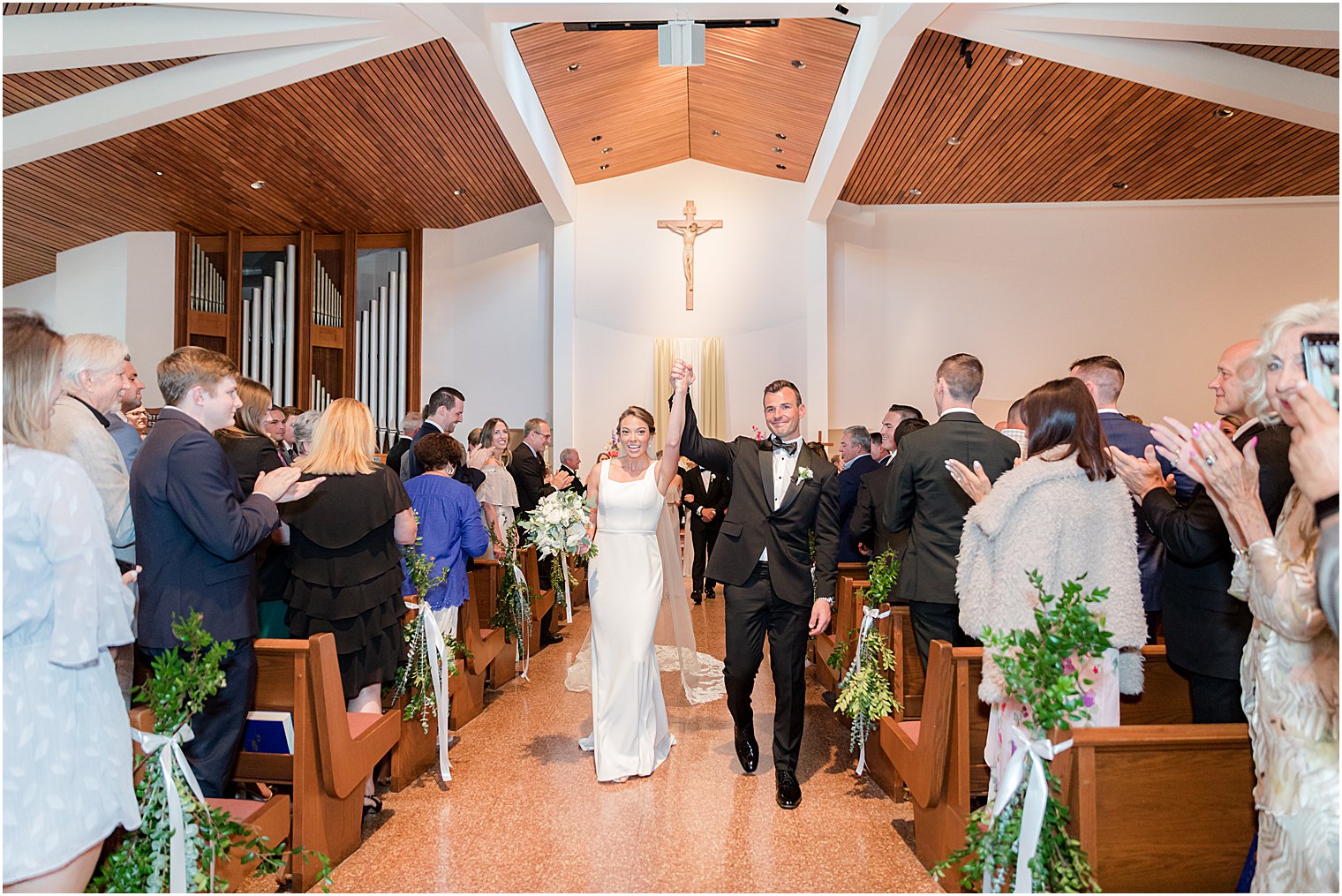 couple holds hands walking up aisle during traditional ceremony at St.Joseph Roman Catholic Church