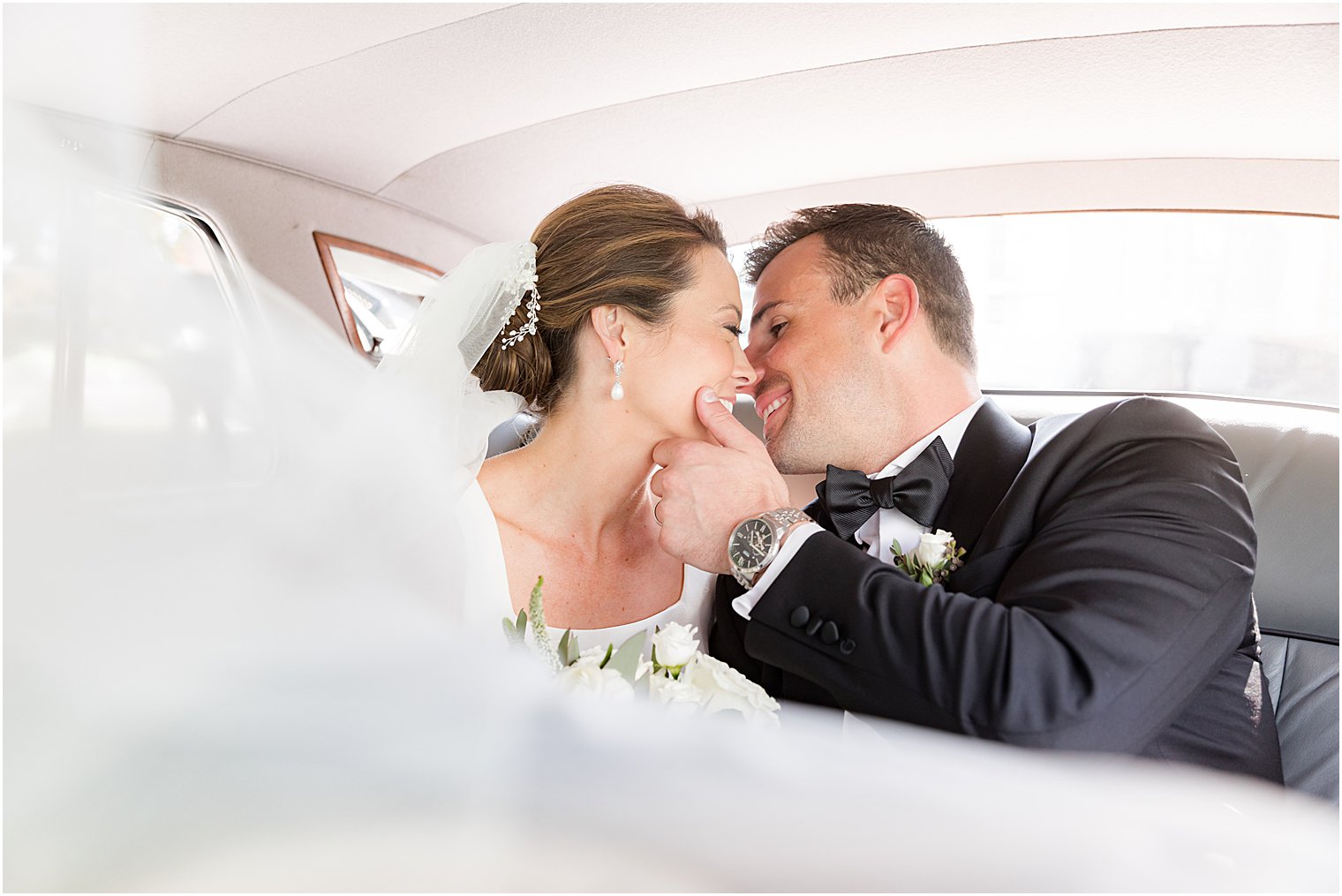 bride and groom kiss in back of classic car