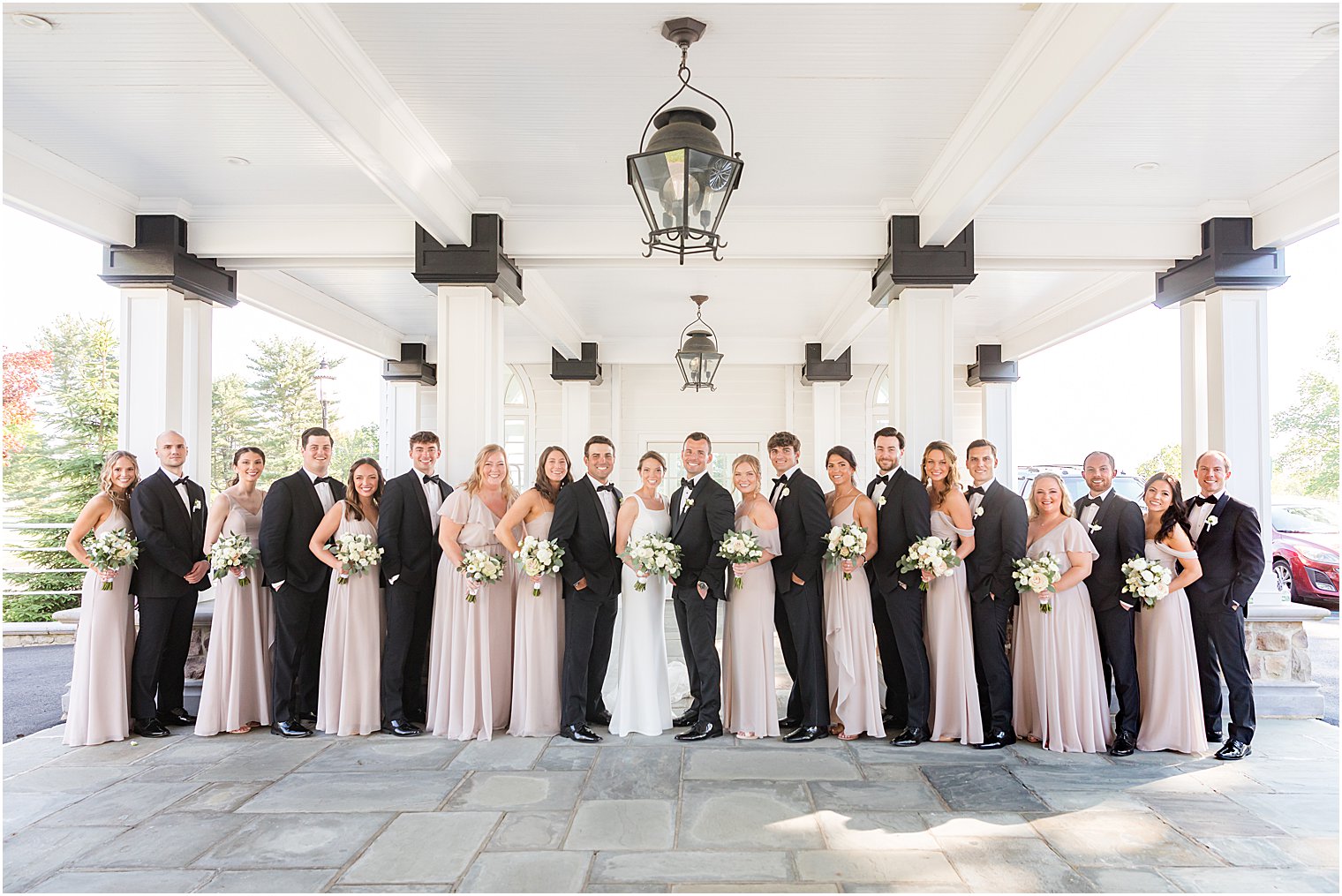 newlyweds pose with wedding party under awning at Ryland Inn