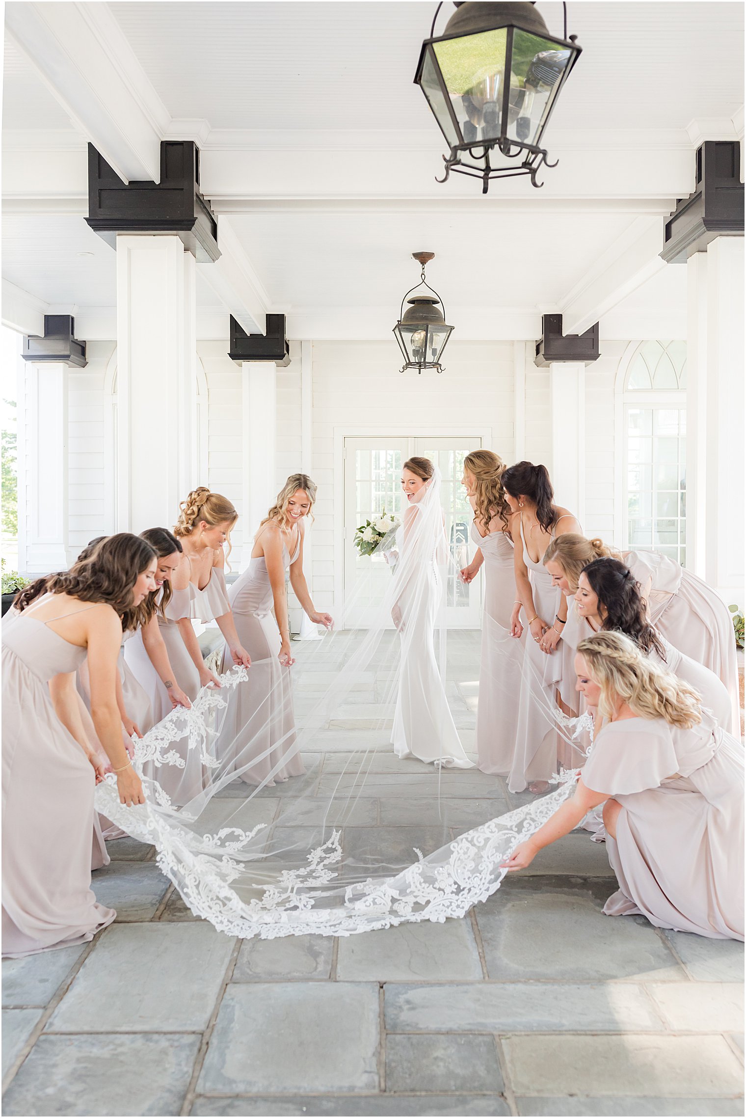 bridesmaids pull bride's veil out under awning at Ryland Inn