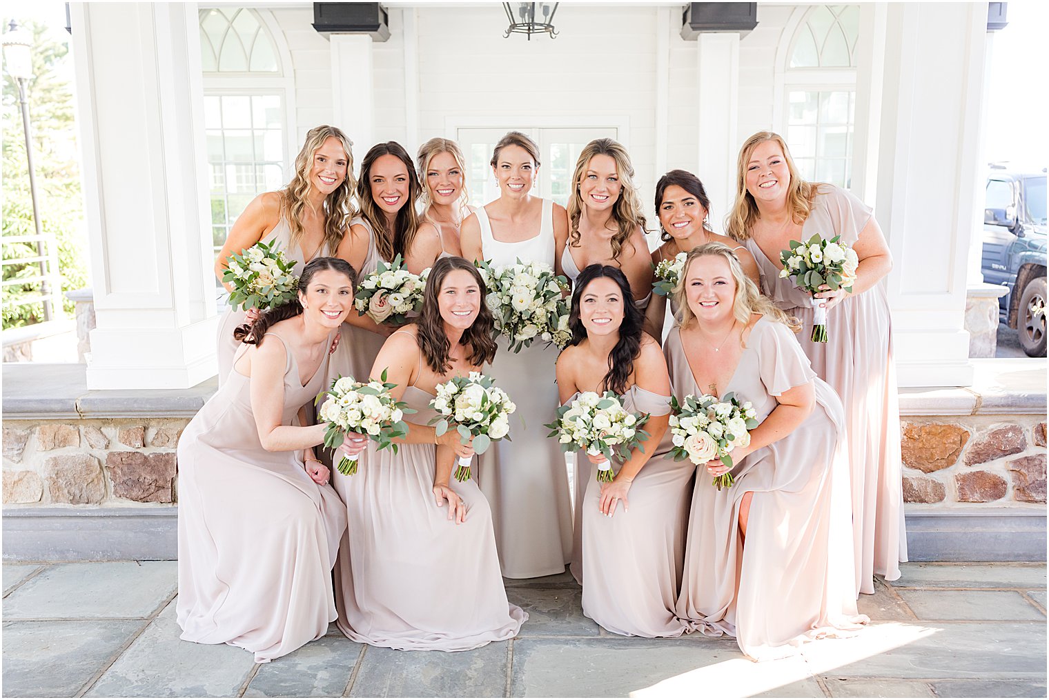 bride poses with bridesmaids in pale pink gowns