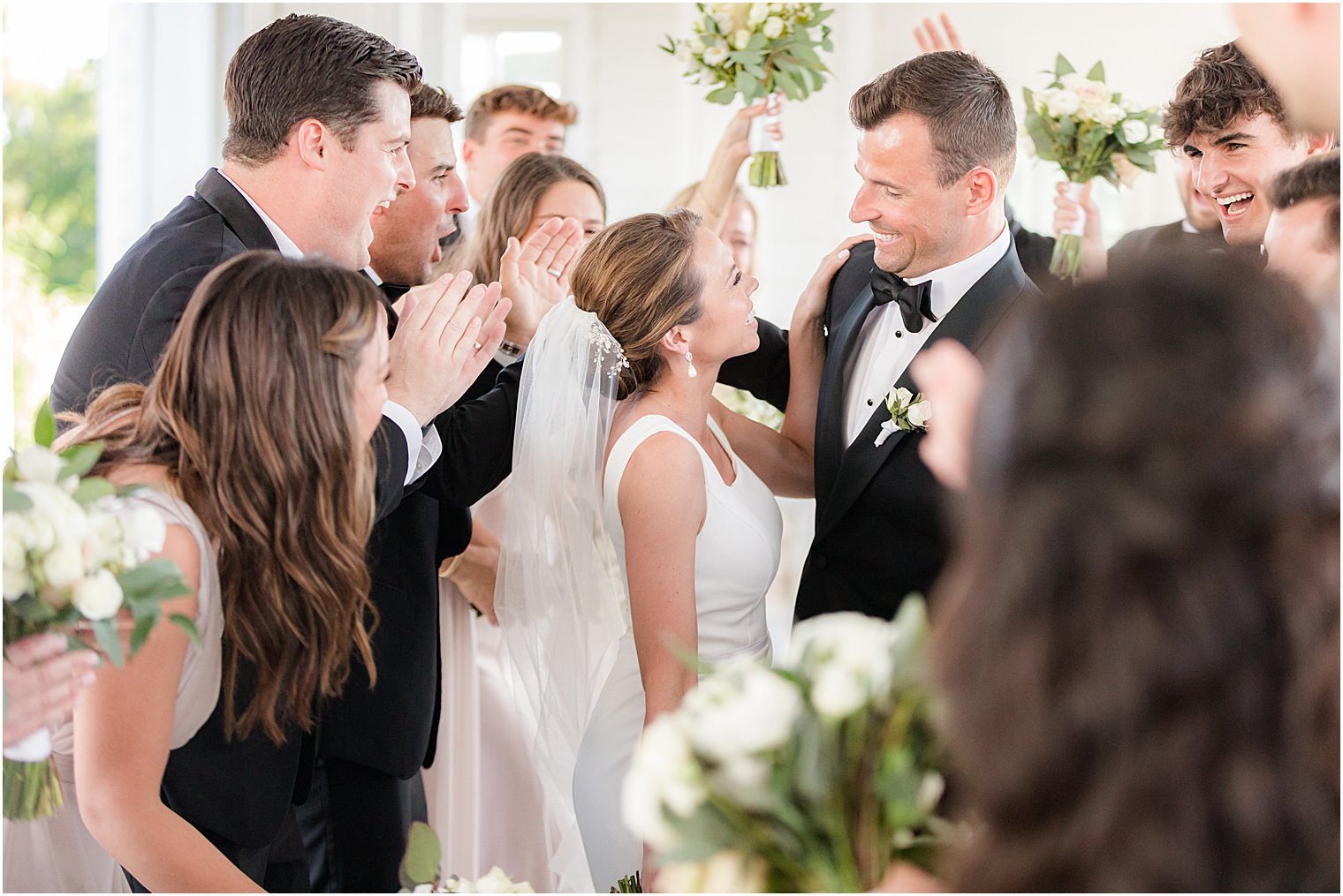 bride and groom smile together with wedding party around them at Ryland Inn