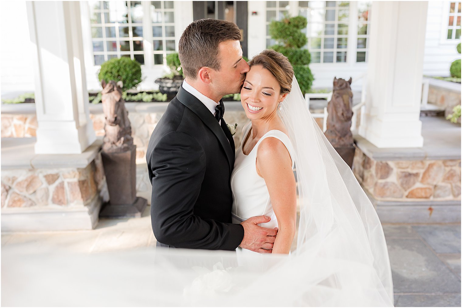 groom kisses bride's forehead outside Ryland Inn