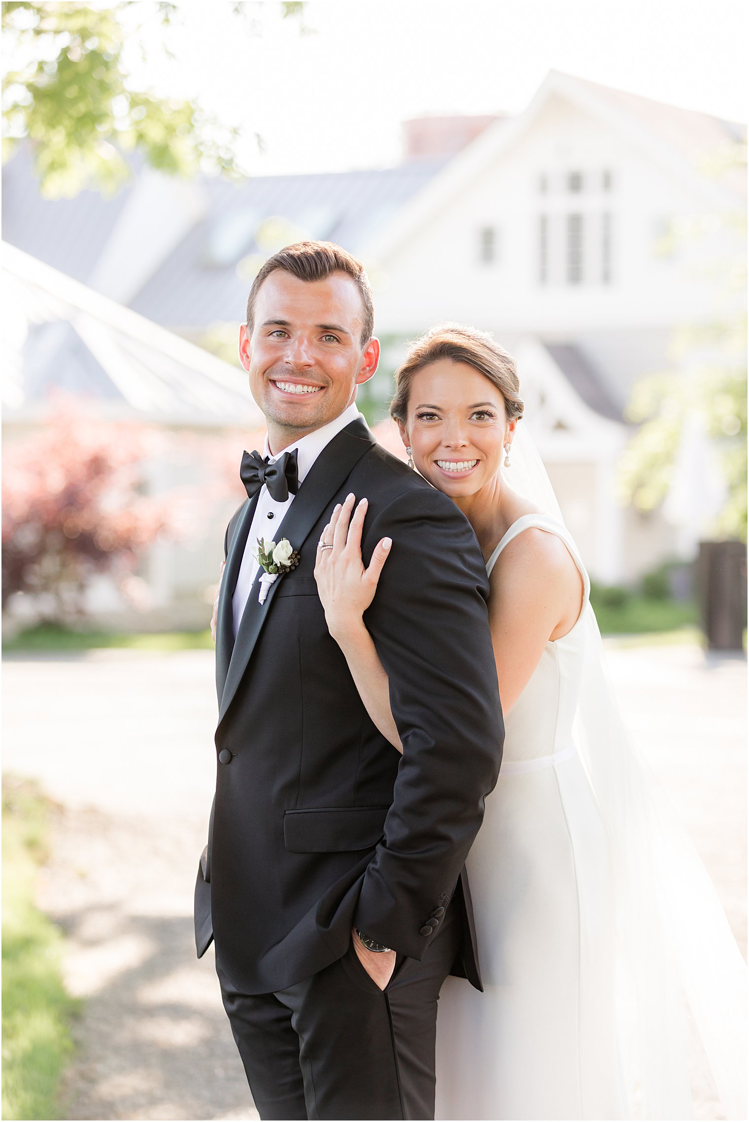 bride hugs groom from behind in front of Ryland Inn in New Jersey