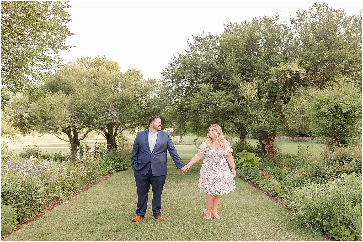 couple holds hands between trees at Skylands Manor