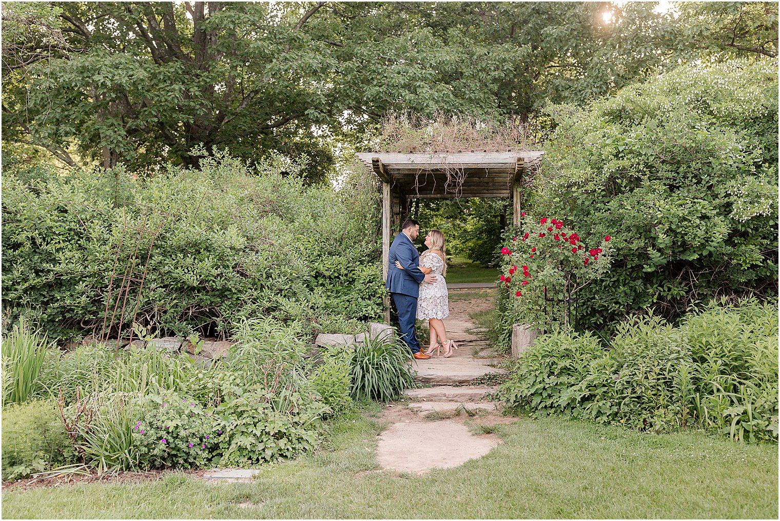 engaged couple hugs in wooden arbor at Skylands Manor