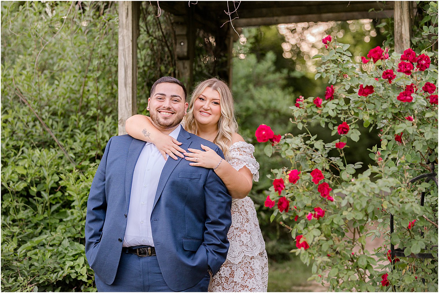 bride hugs groom from behind during summer engagement session at Skylands Manor