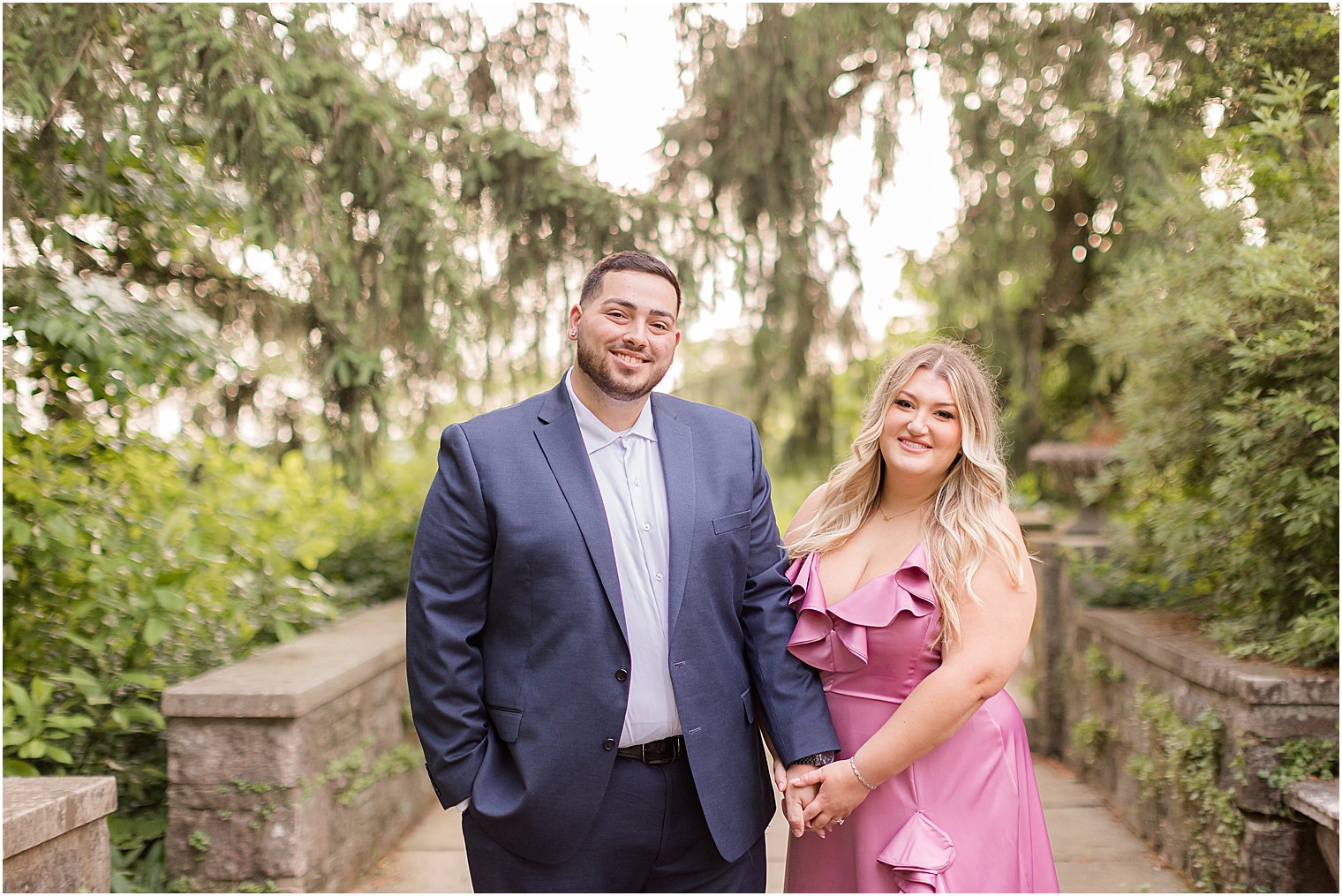 couple holds hands on stone walkway during summertime Skylands Manor engagement session