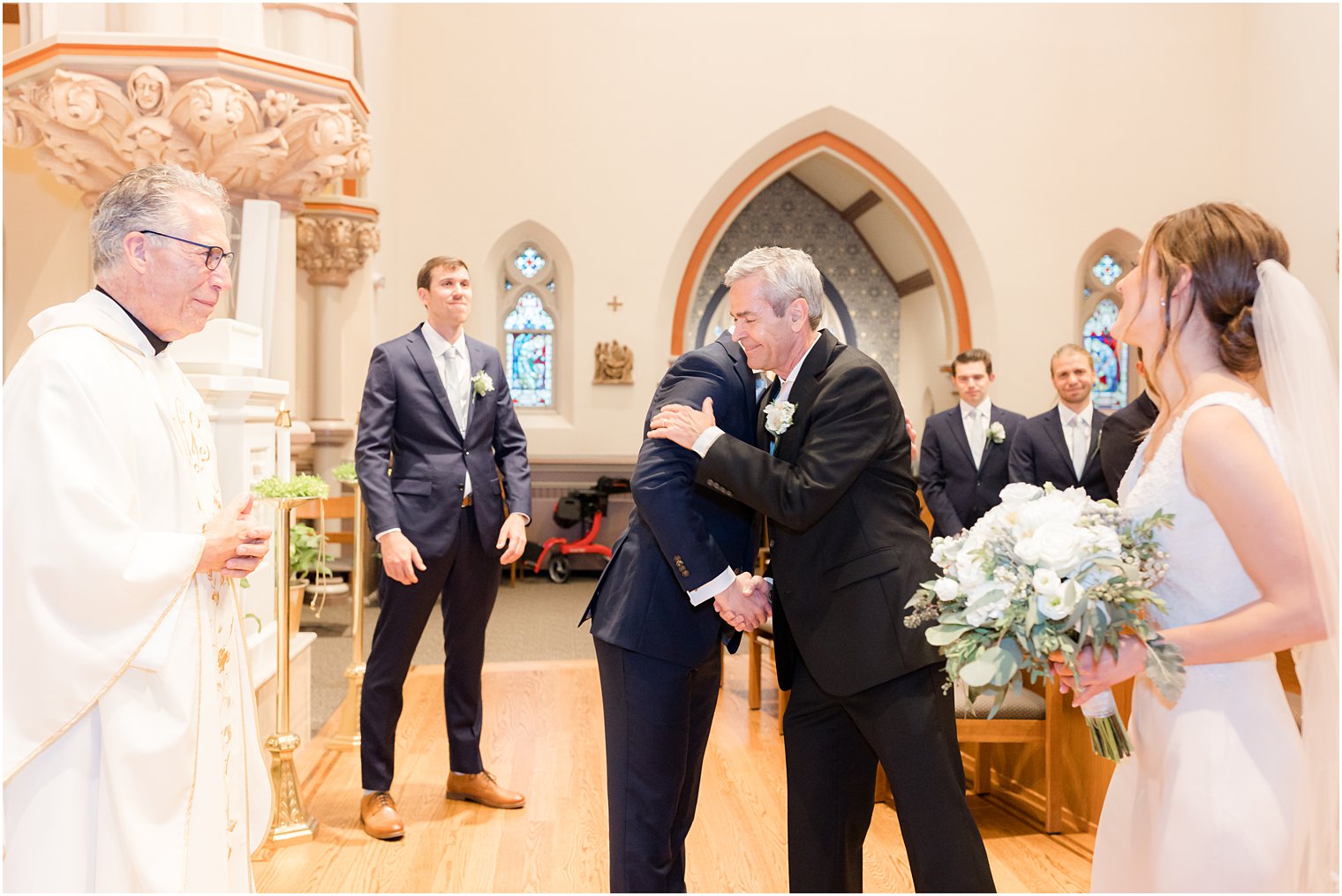 groom hugs bride's father during ceremony at St. Vincent Martyr Church