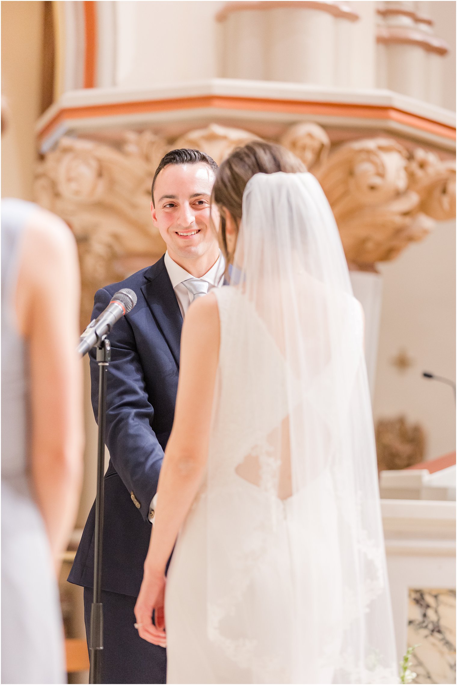 groom smiles at bride during wedding ceremony at St. Vincent Martyr Church