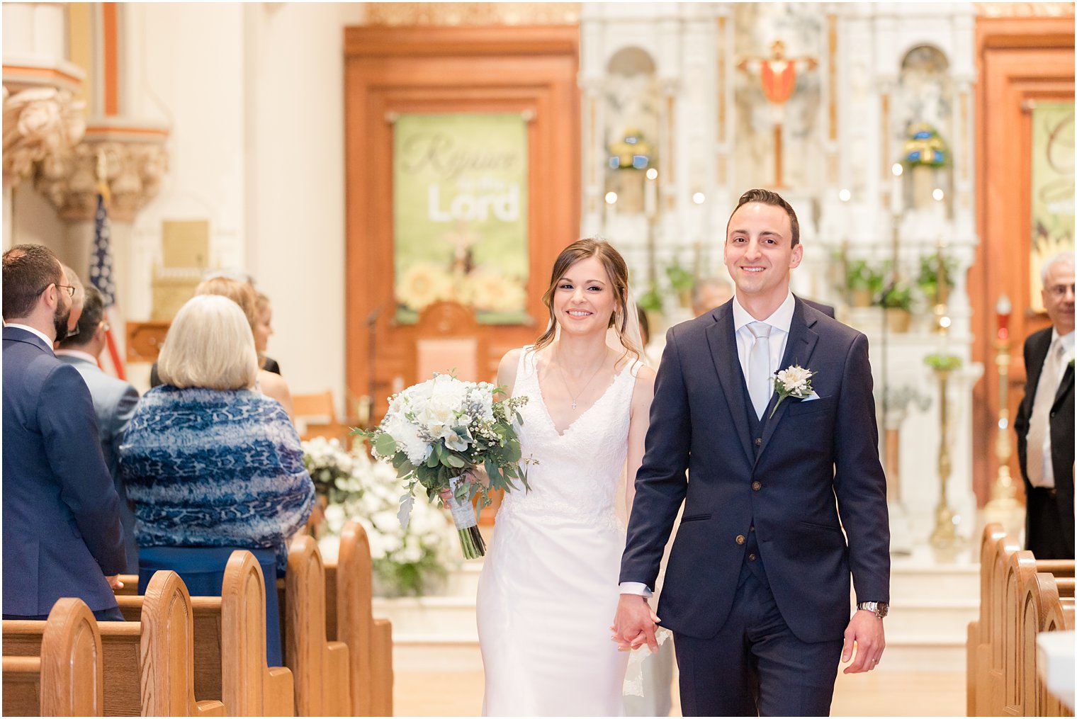 couple holds hands walking up aisle at St. Vincent Martyr Church