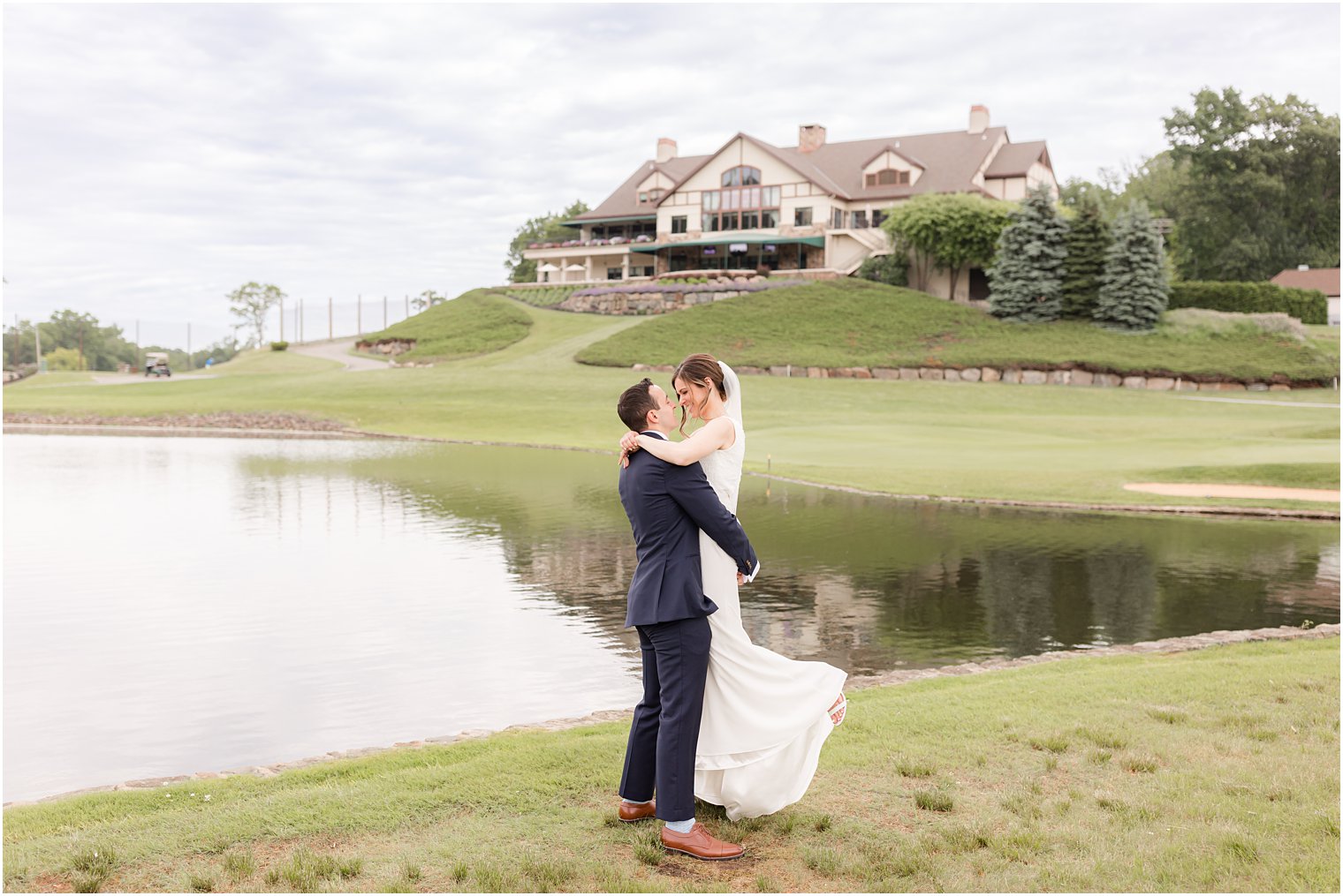 groom lifts bride by lake at Spring Brook Country Club