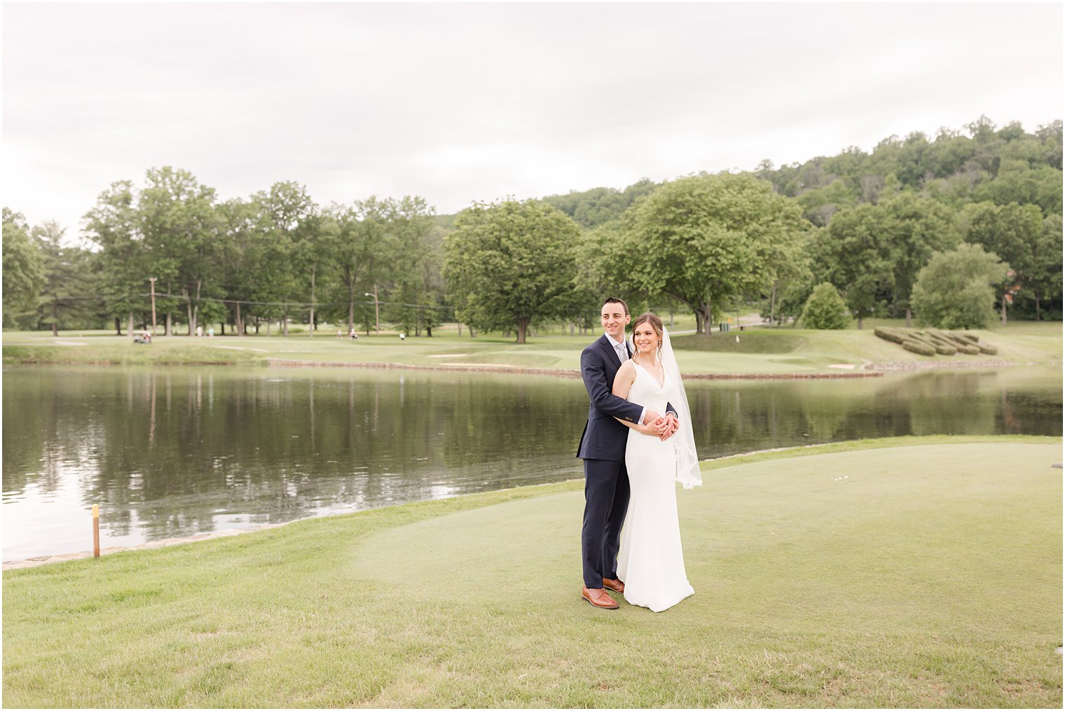 newlyweds hug by lake at Spring Brook Country Club