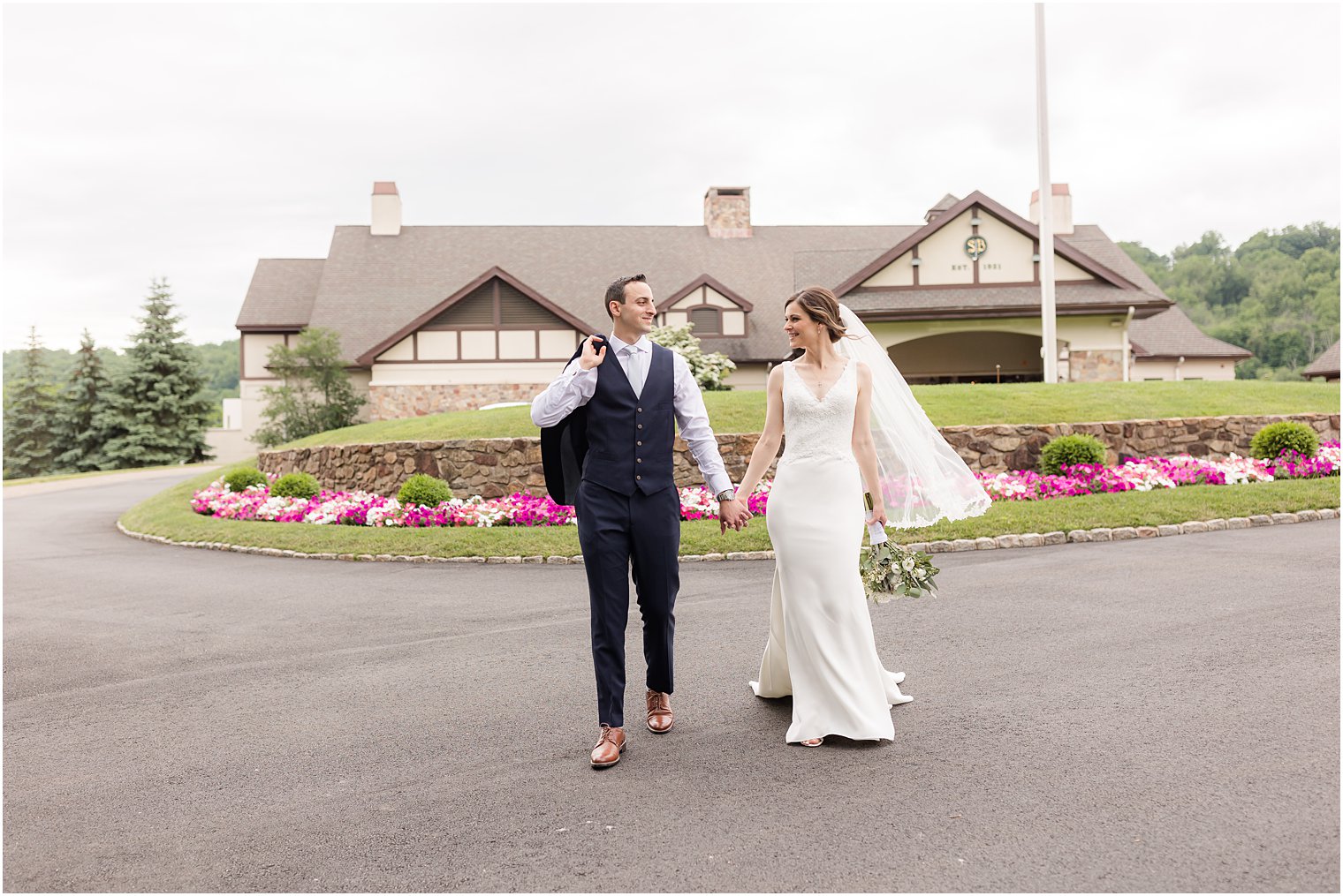 newlyweds hold hands walking outside Spring Brook Country Club