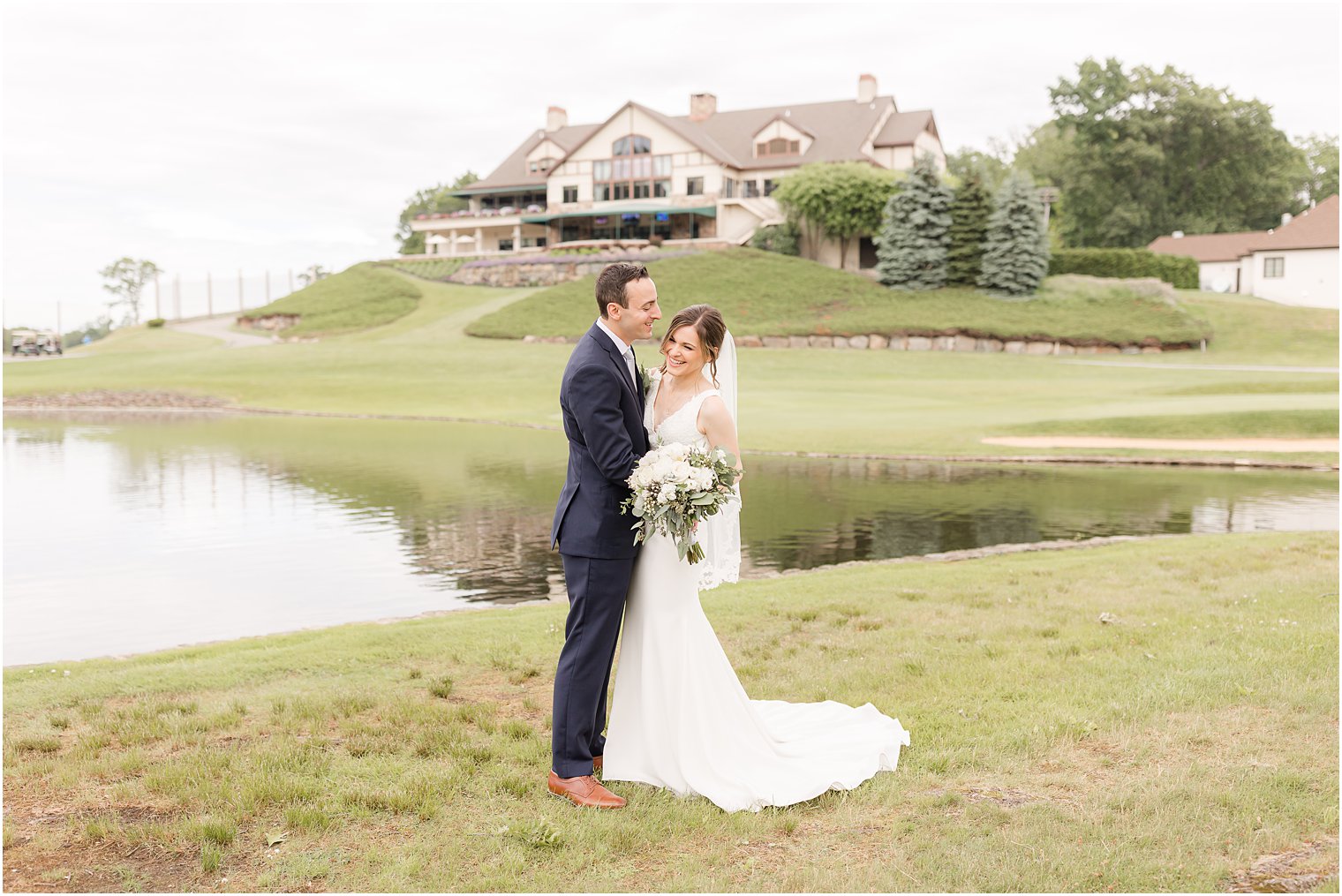 bride and groom pose along lake at Spring Brook Country Club