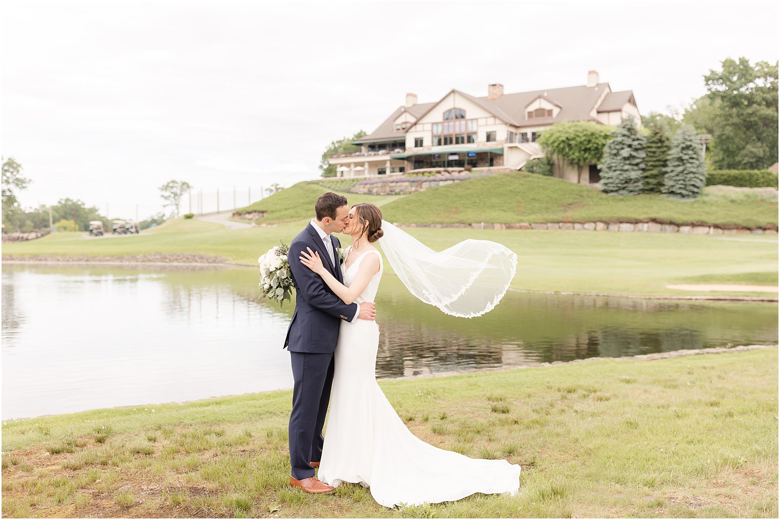 bride and groom kiss while bride's veil floats at Spring Brook Country Club