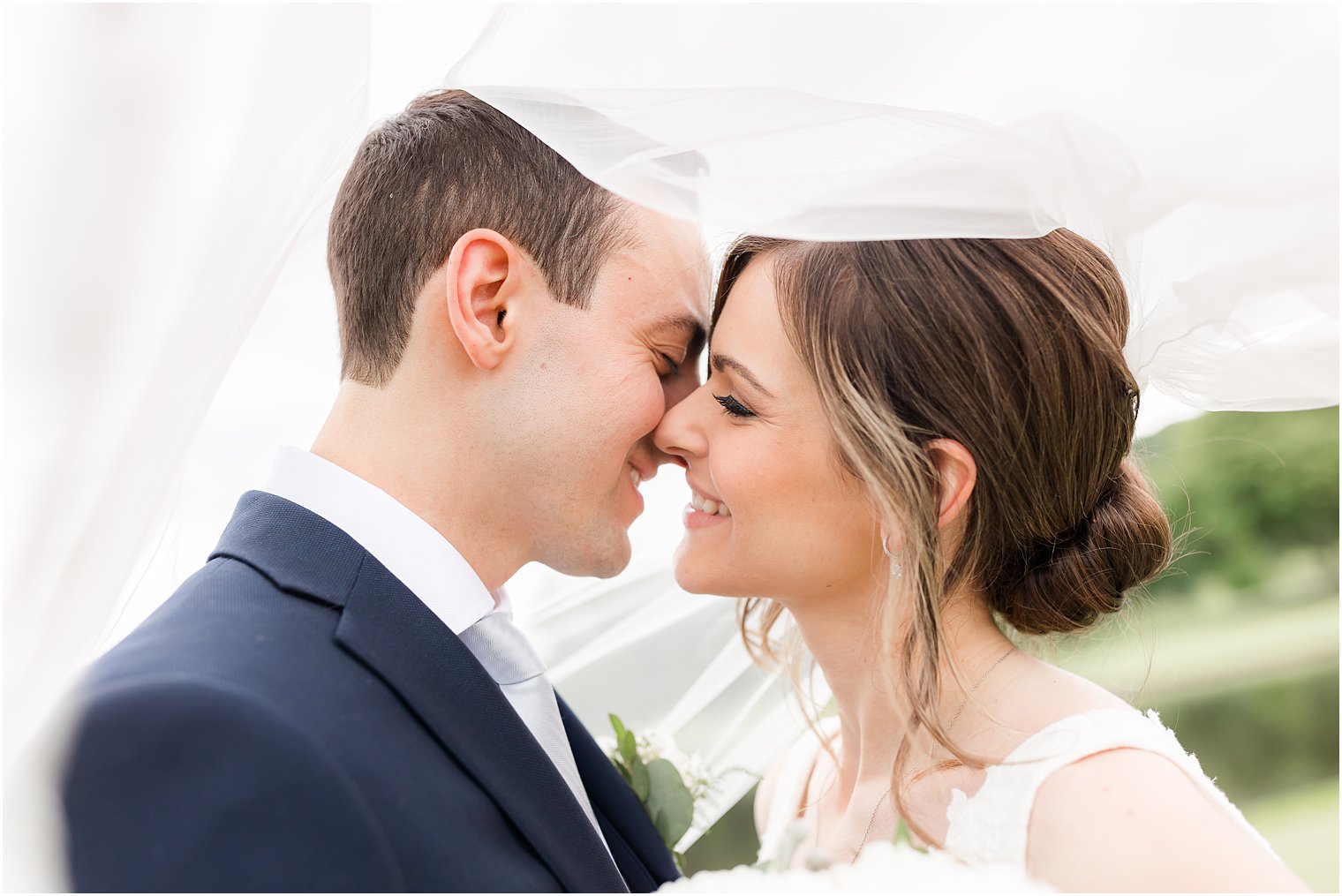 newlyweds lean in for kiss under bride's veil at Spring Brook Country Club