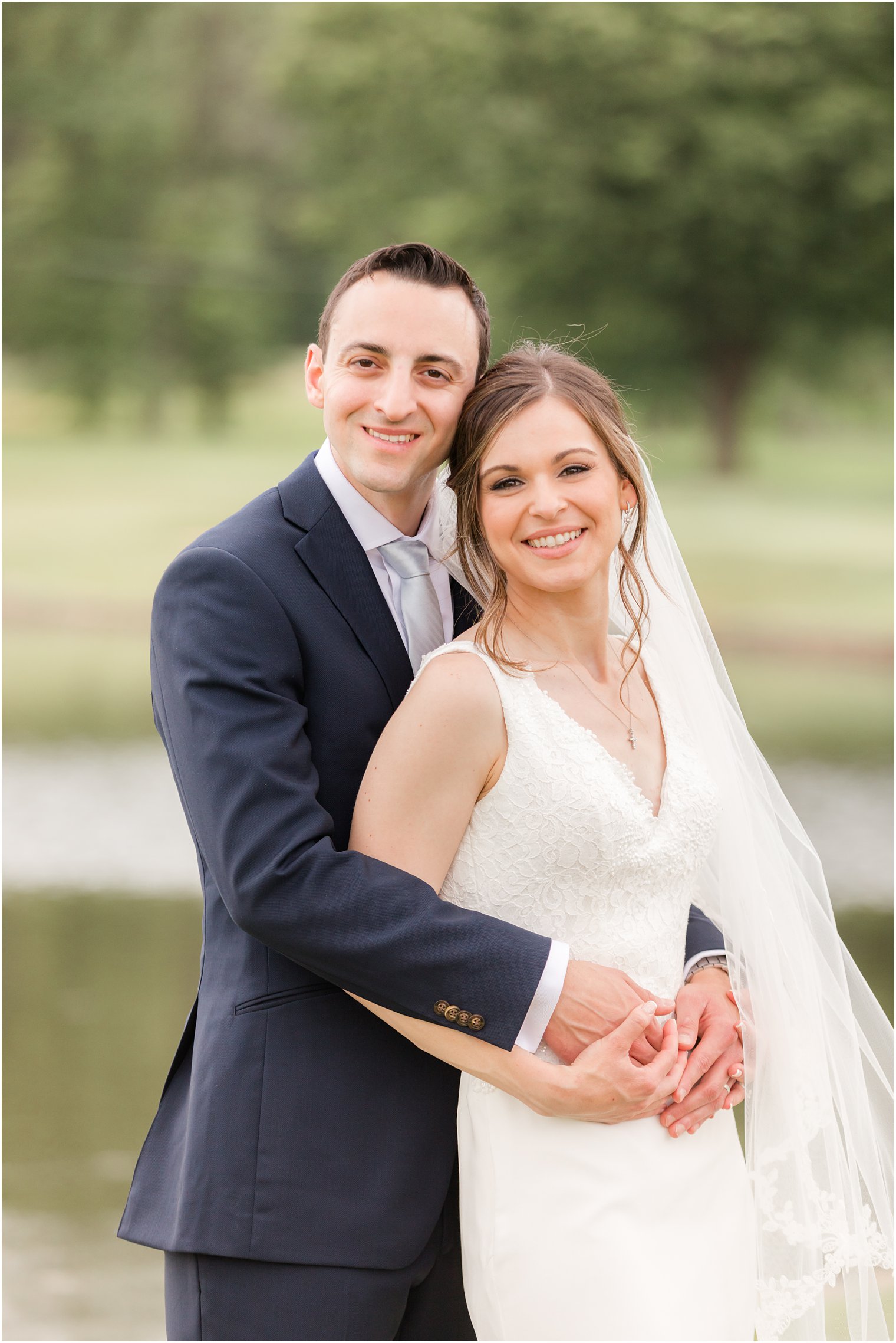 groom hugs bride from behind during Spring Brook Country Club wedding portraits 