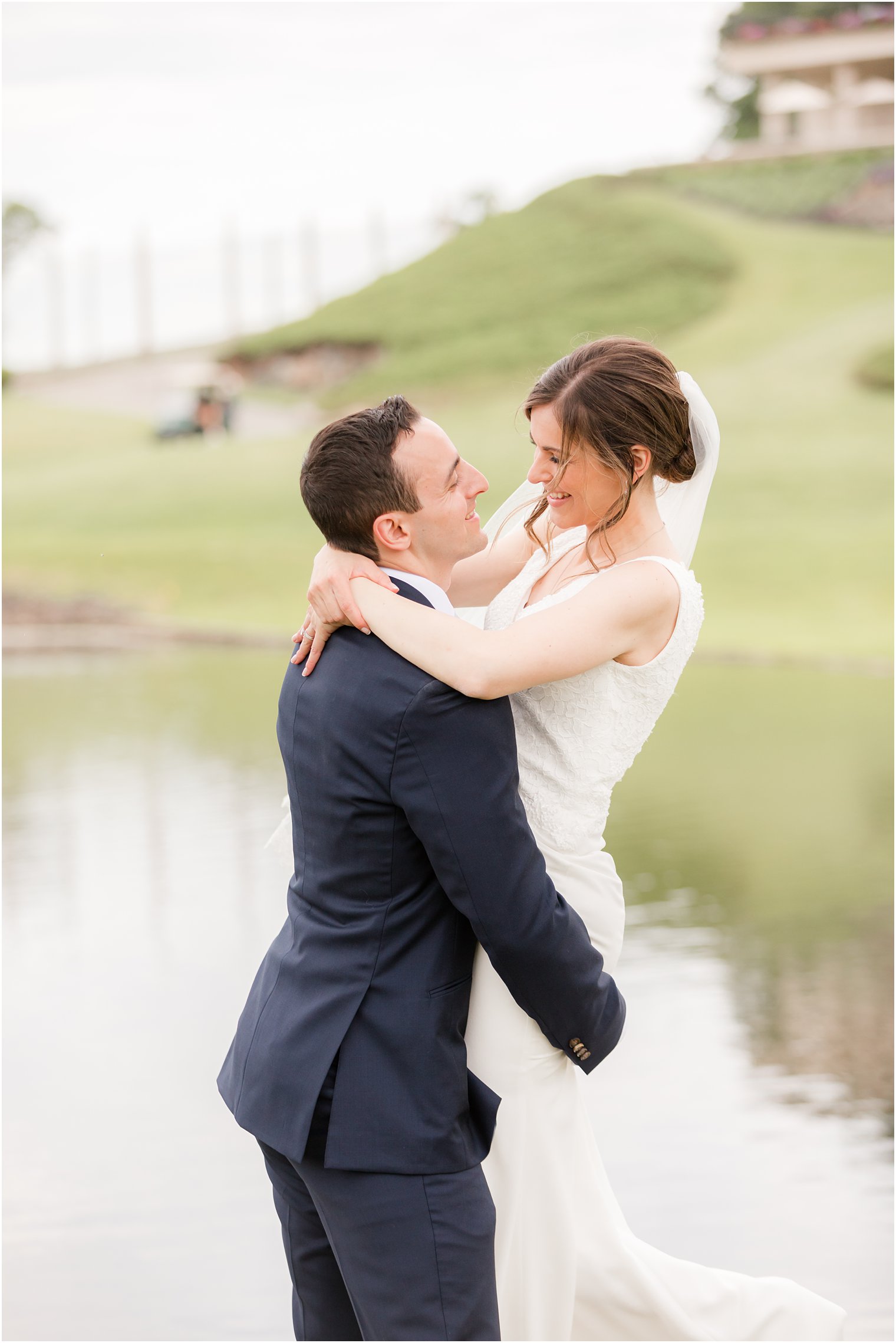 bride looks at groom while he picks her up at Spring Brook Country Club
