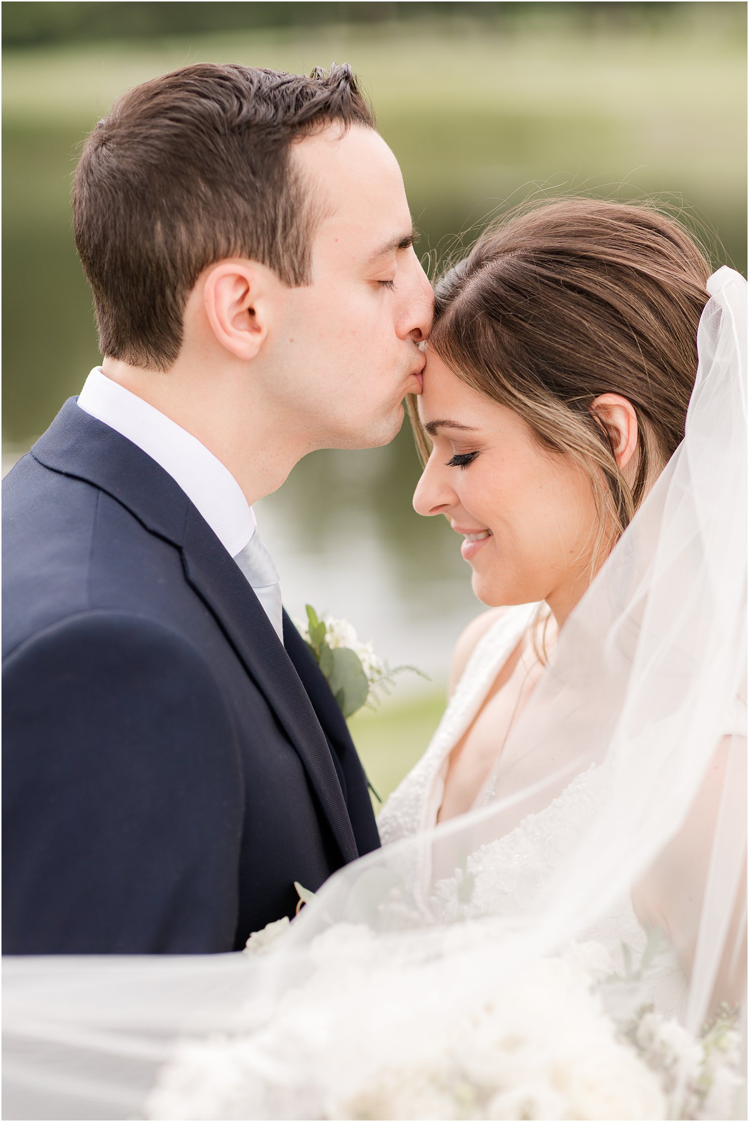 groom kisses bride's forehead during NJ wedding photos