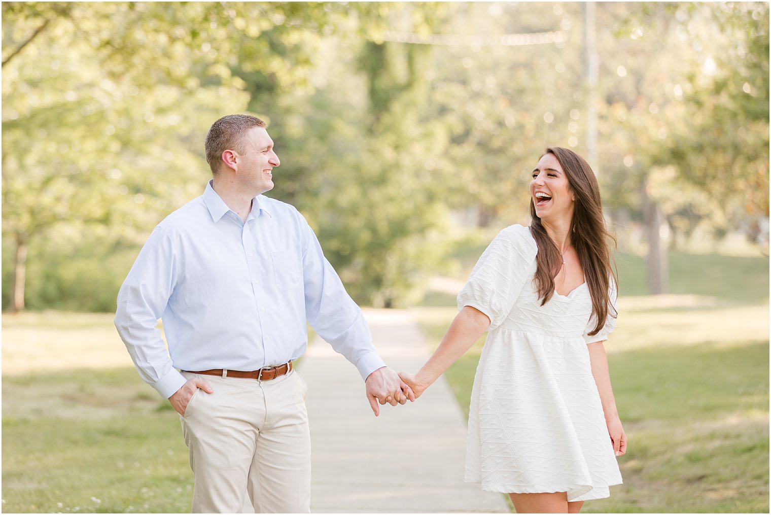 engaged couple laughs walking through Spring Lake park 