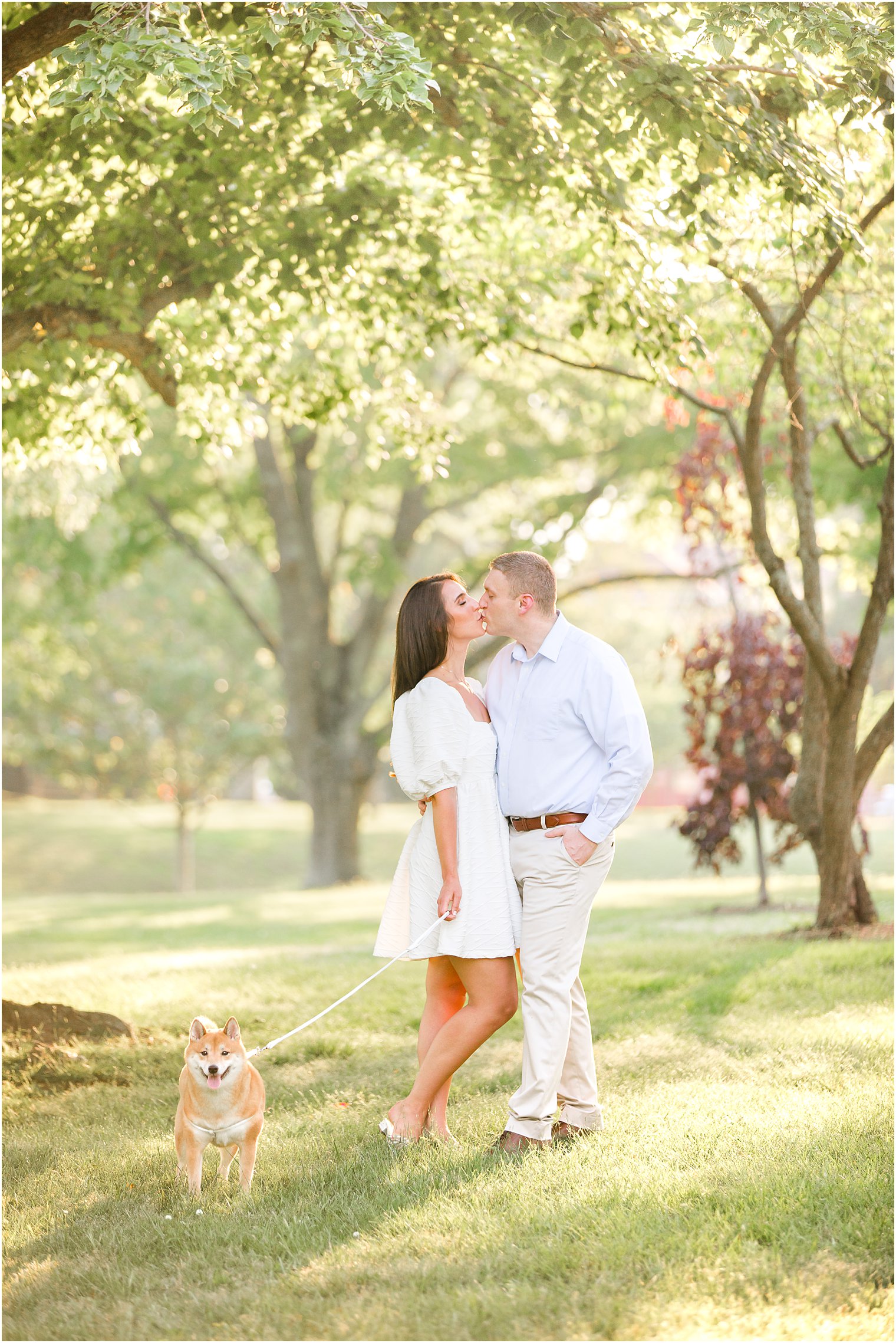 couple kisses while dog stands by them in Spring Lake Park