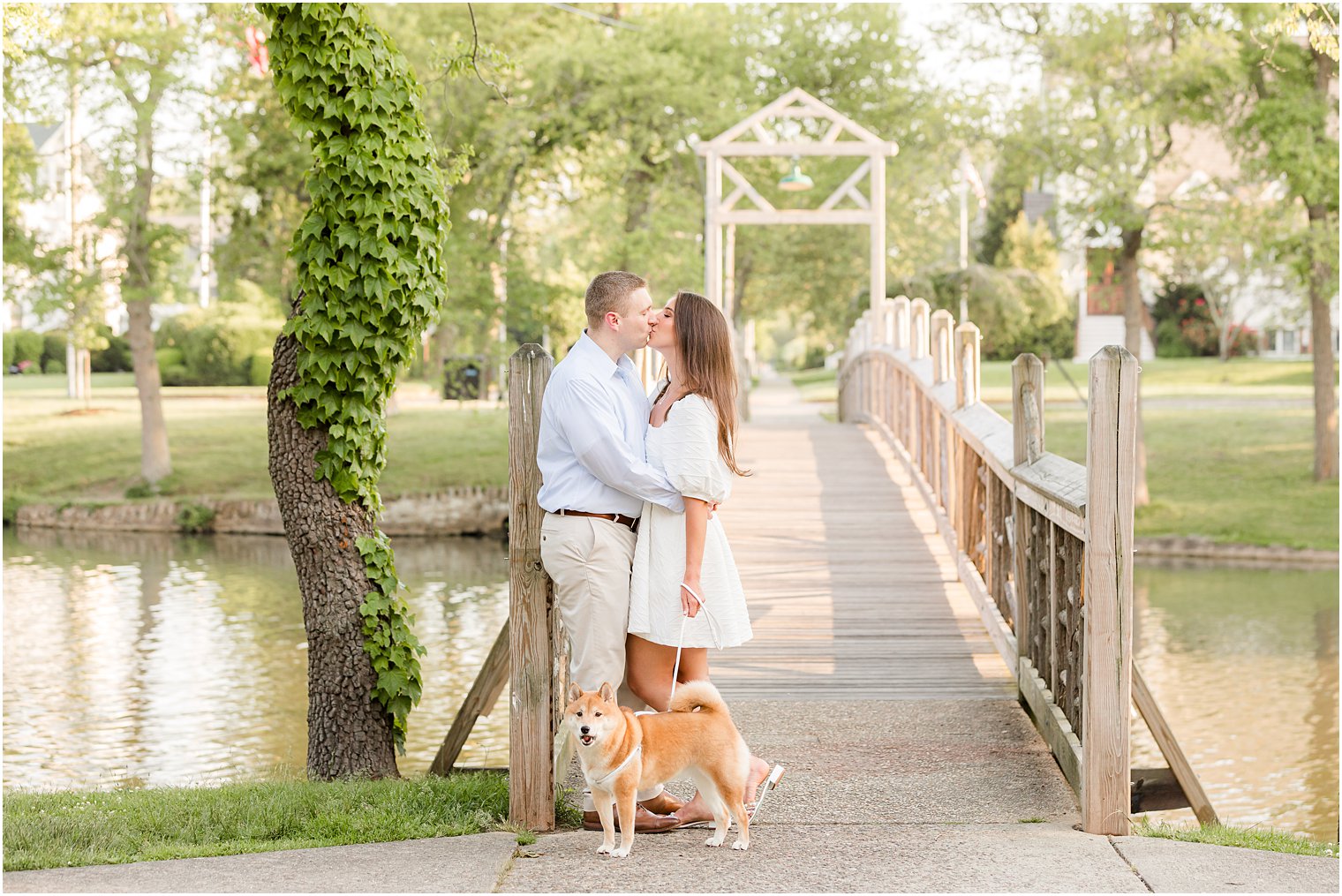 couple kisses at foot of bridge with dog by them