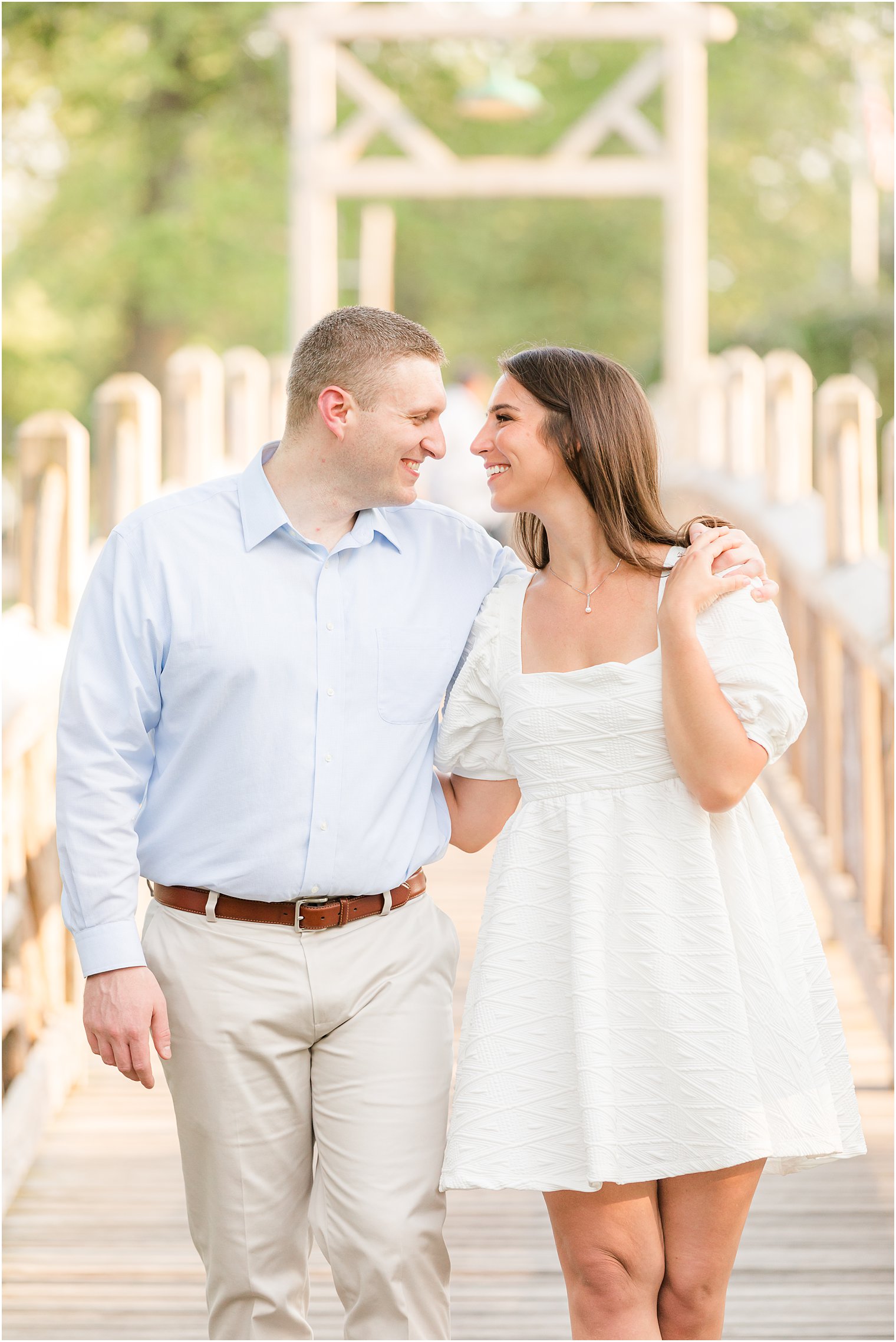 couple leans together on bridge during Spring Lake engagement session