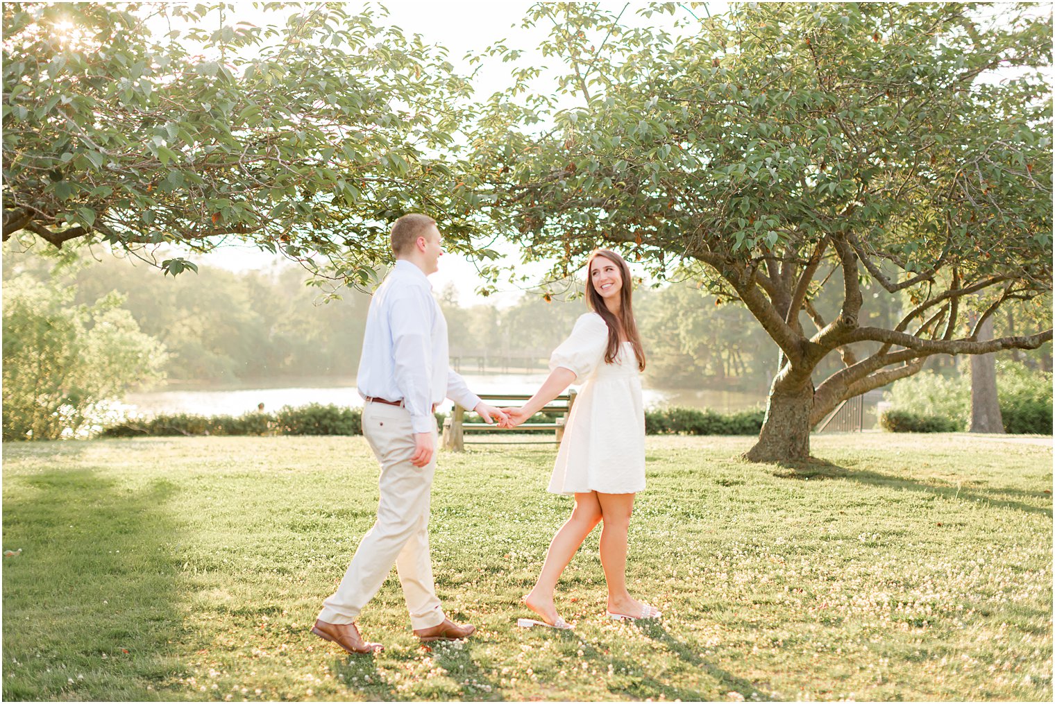 engaged couple holds hands walking through Spring Lake Park