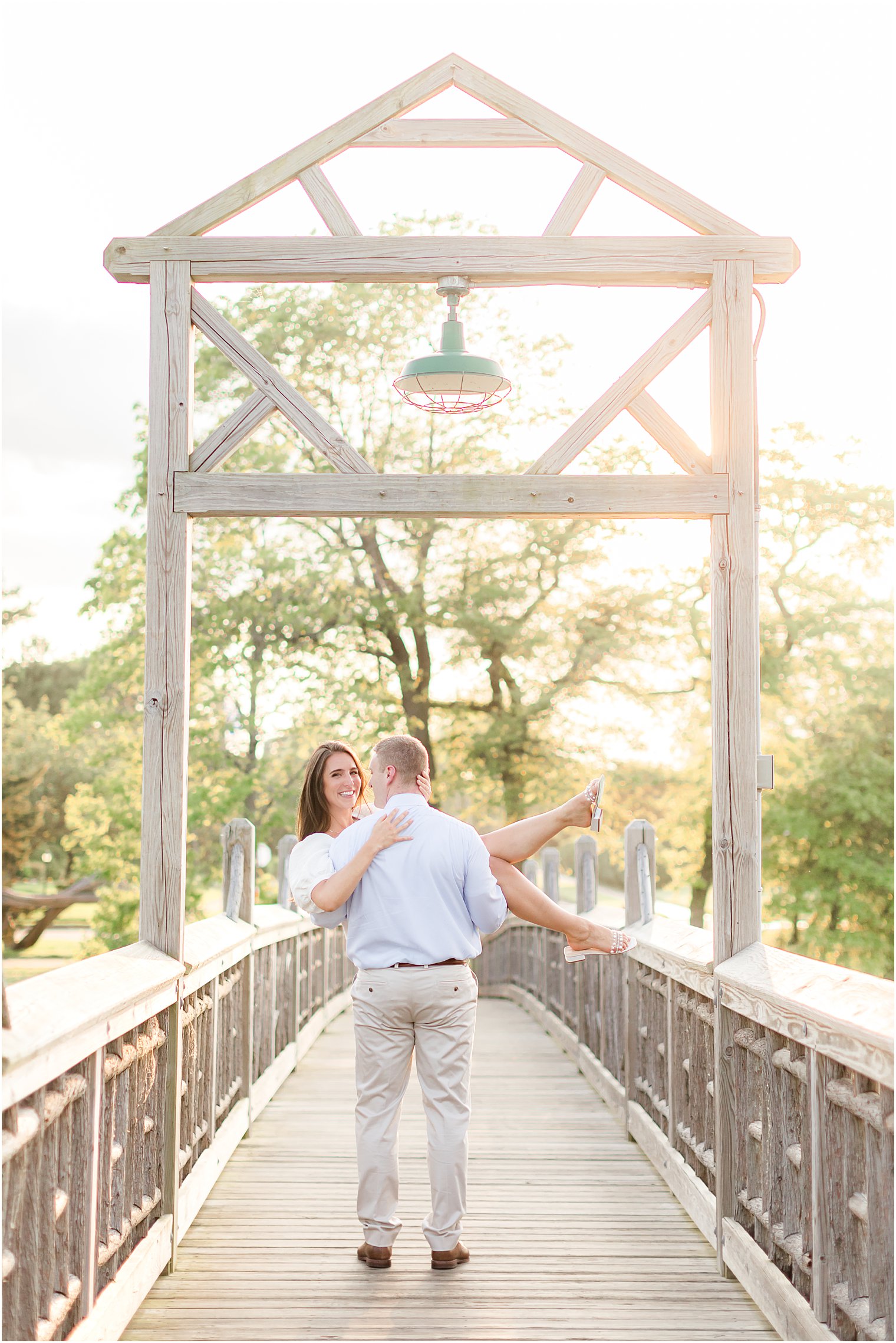 man lifts woman over wooden bridge during 