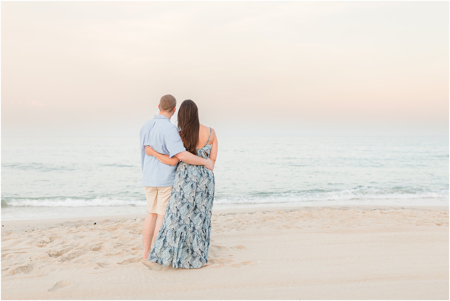 engaged couple stands together looking at water in Spring Lake NJ