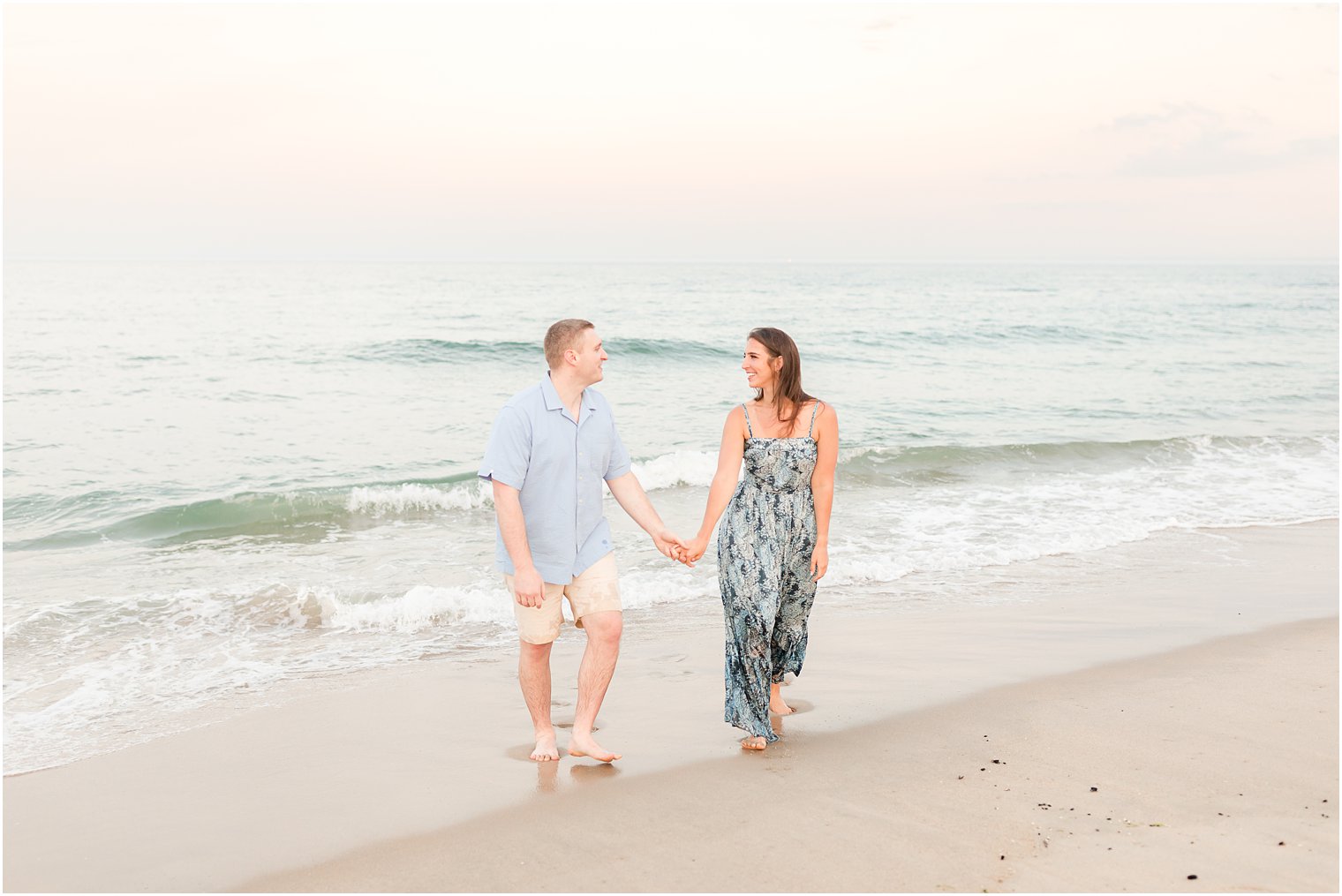 engaged copule walks along beach during Spring Lake engagement session