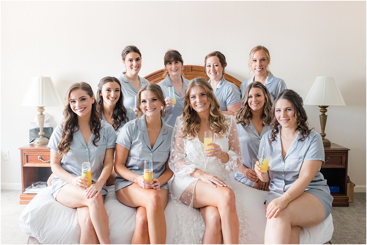 bride sits with bridesmaids in blue robes on bed at The Mill Lakeside Manor