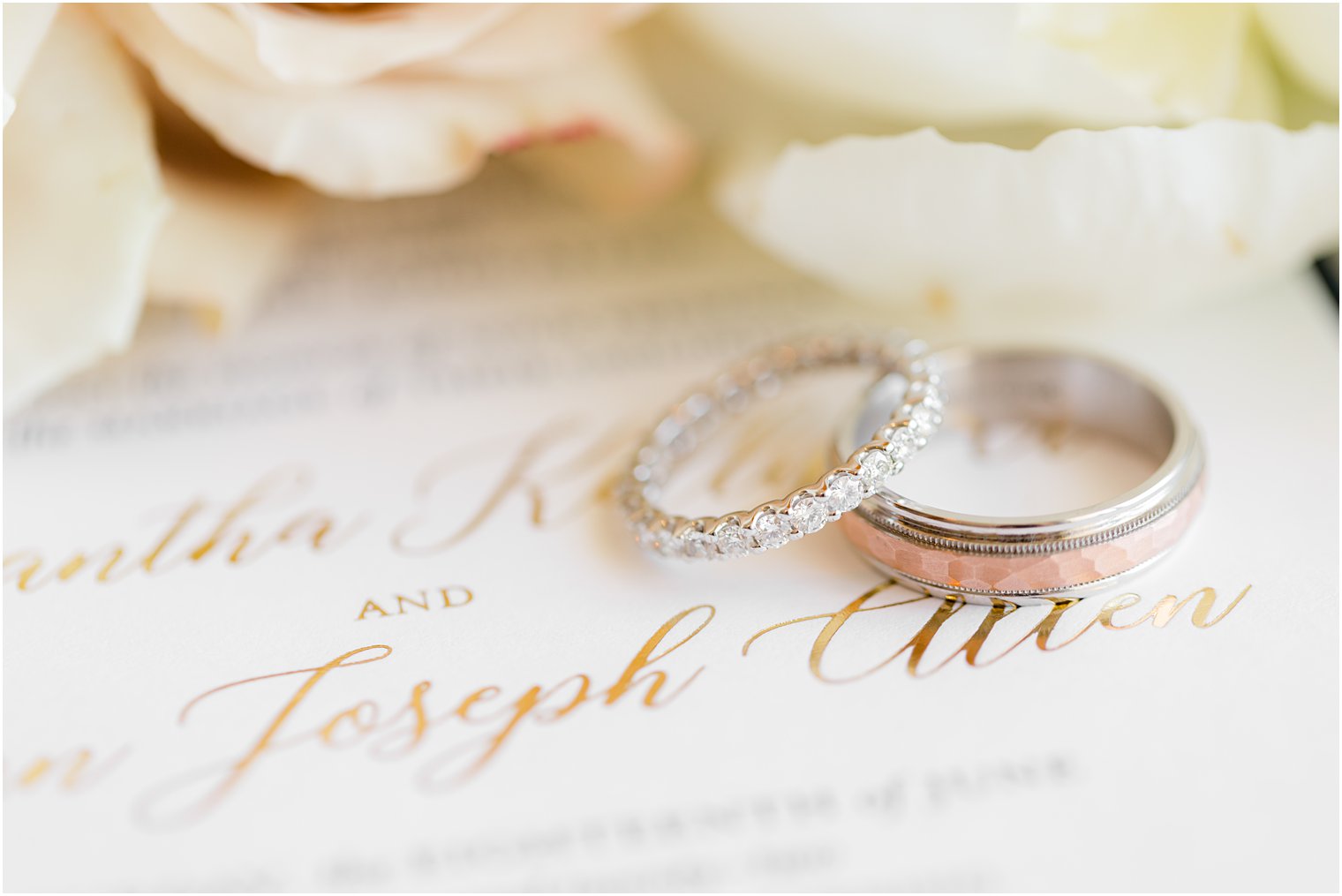 wedding bands rest on gold script of invitation at The Mill Lakeside Manor