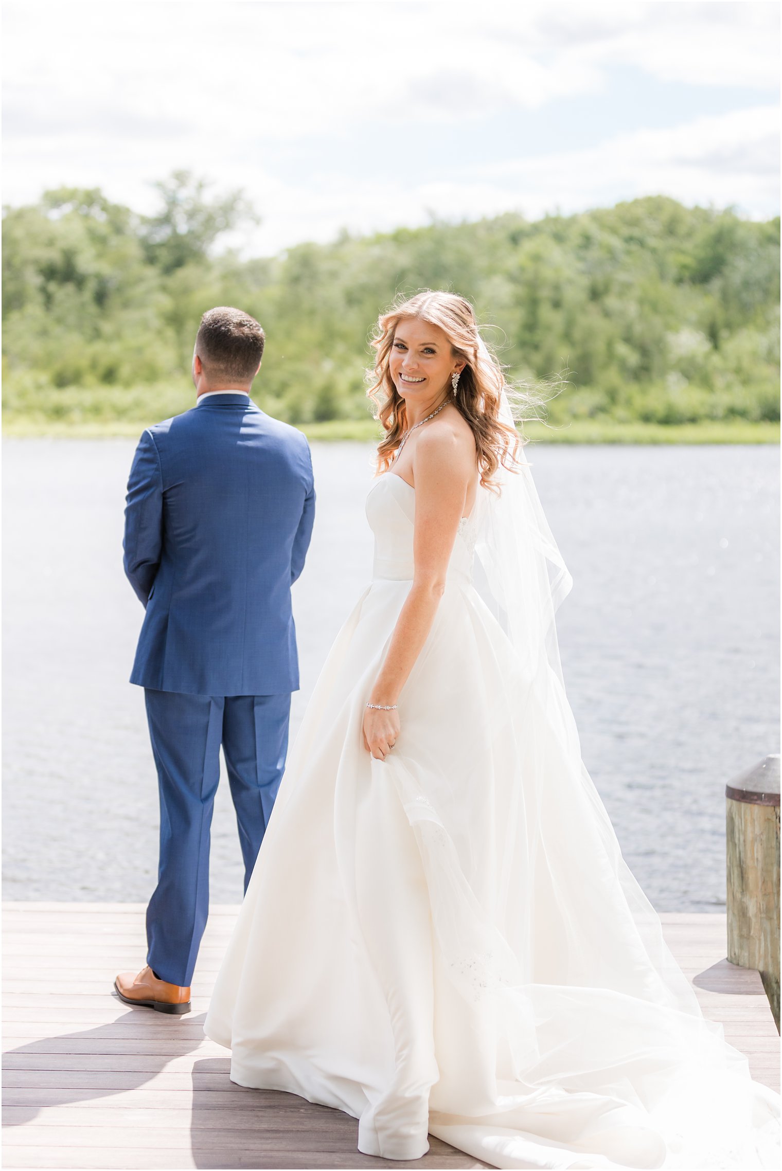 bride approaches groom for first look on dock at The Mill Lakeside Manor