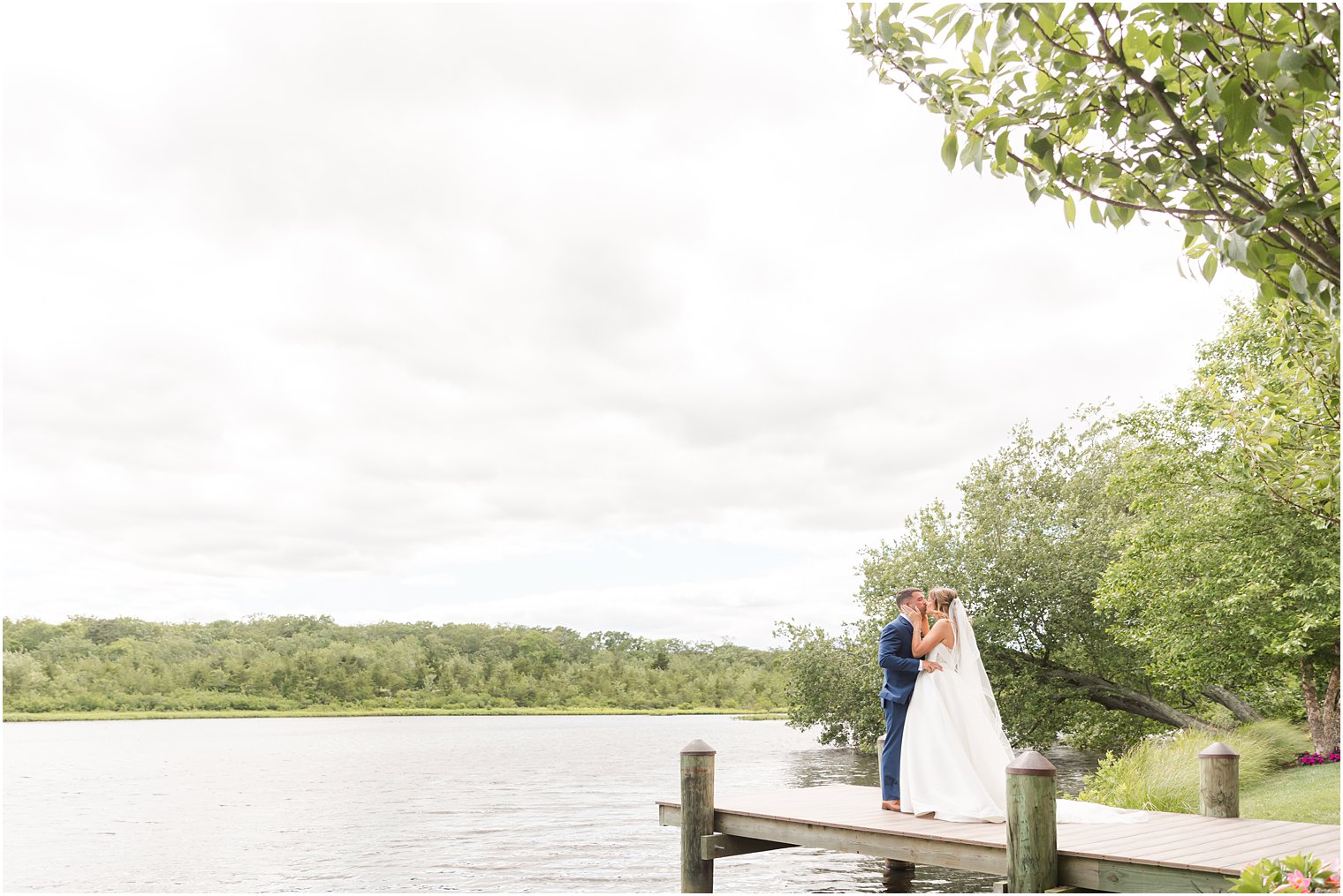 bride and groom kiss on dock at The Mill Lakeside Manor