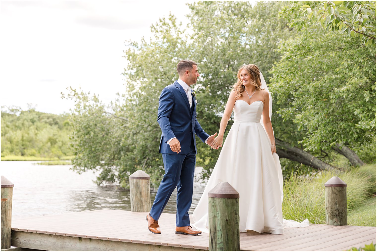 couple holds hands walking on dock at The Mill Lakeside Manor