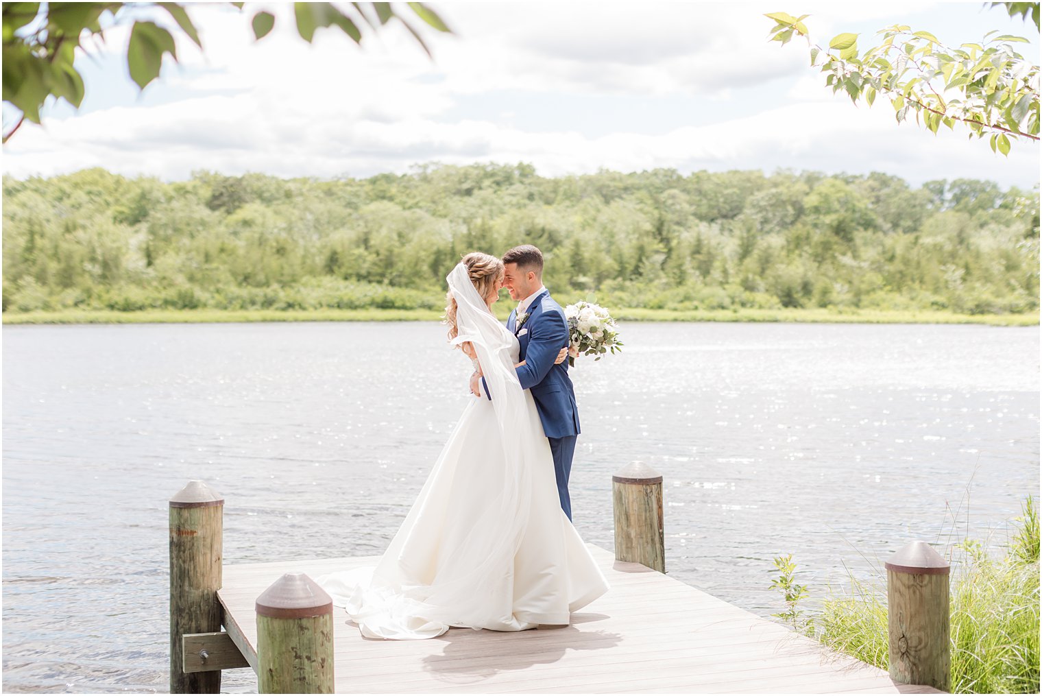 bride and groom lean in for a kiss on dock during summer wedding portraits at The Mill Lakeside Manor
