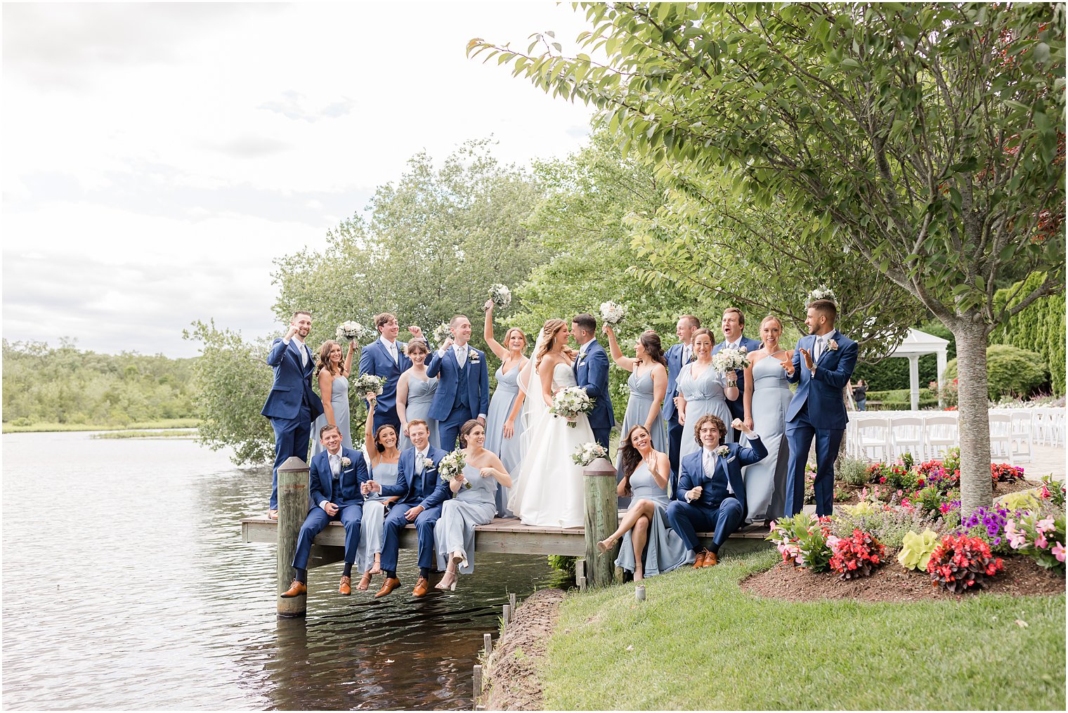 newlyweds and wedding party cheer standing on dock at The Mill Lakeside Manor