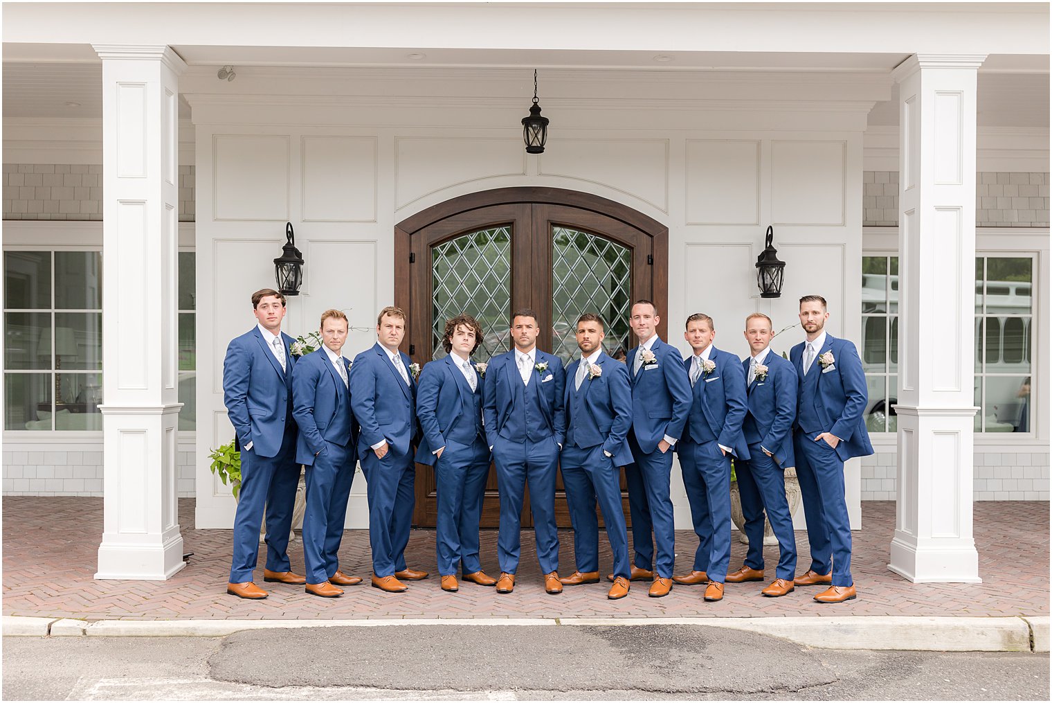 groomsmen pose outside The Mill Lakeside Manor in navy suits