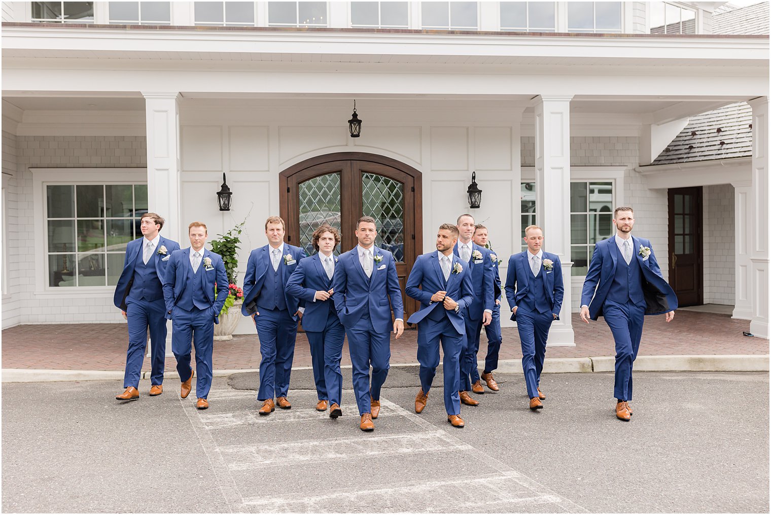 groom walks with groomsmen in front of The Mill Lakeside Manor