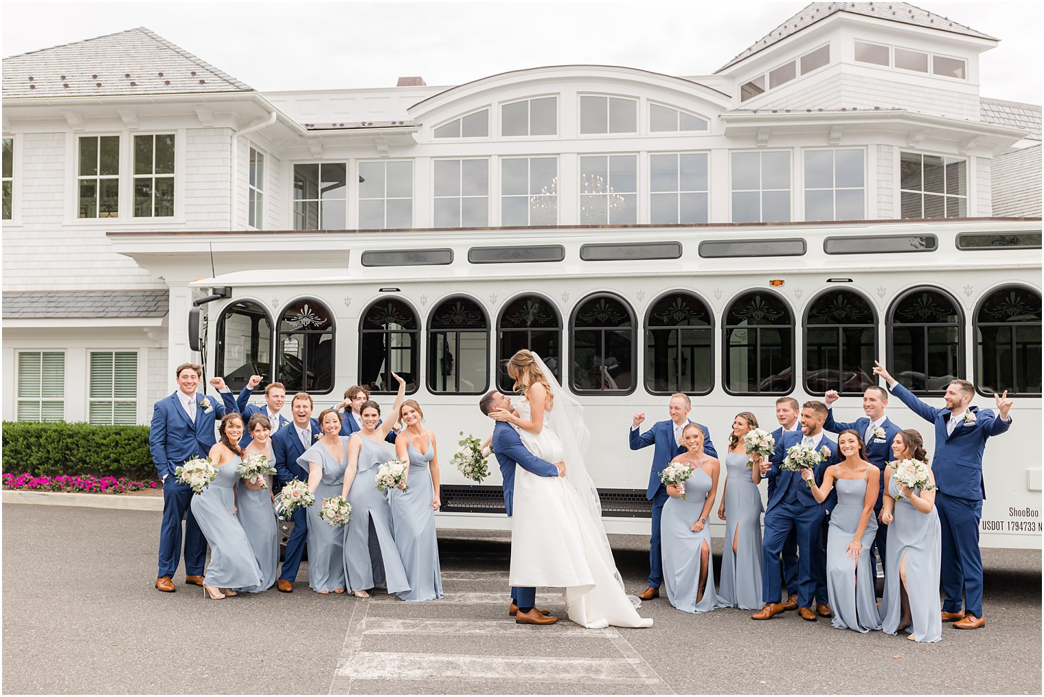 groom lifts bride by white trolley outside The Mill Lakeside Manor