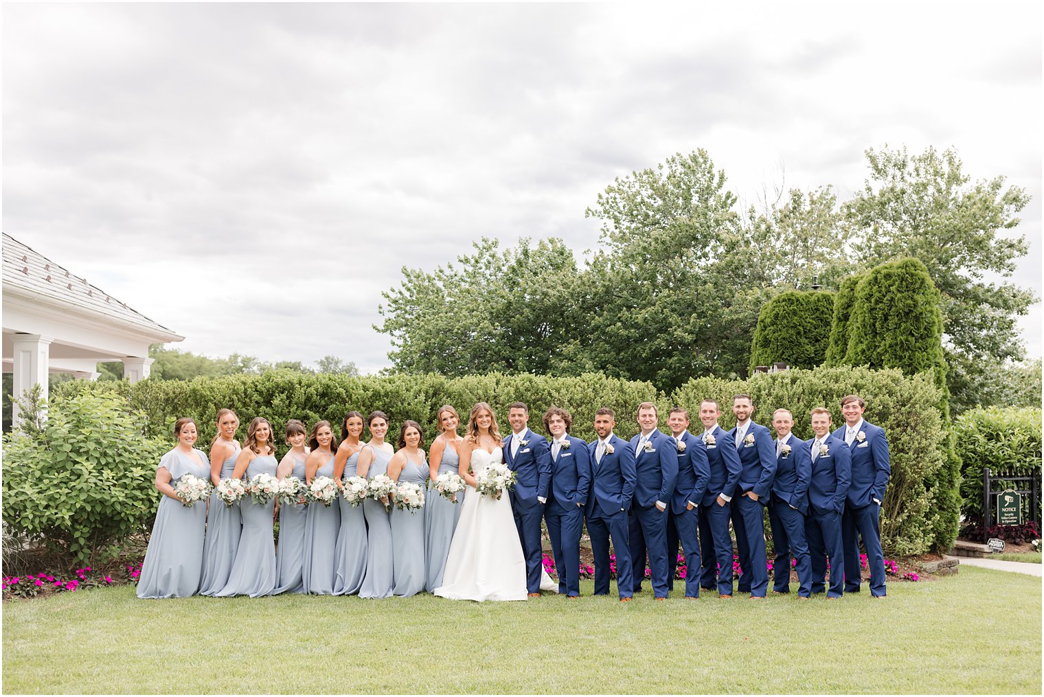 newlyweds stand with wedding party in light blue dresses and navy suits