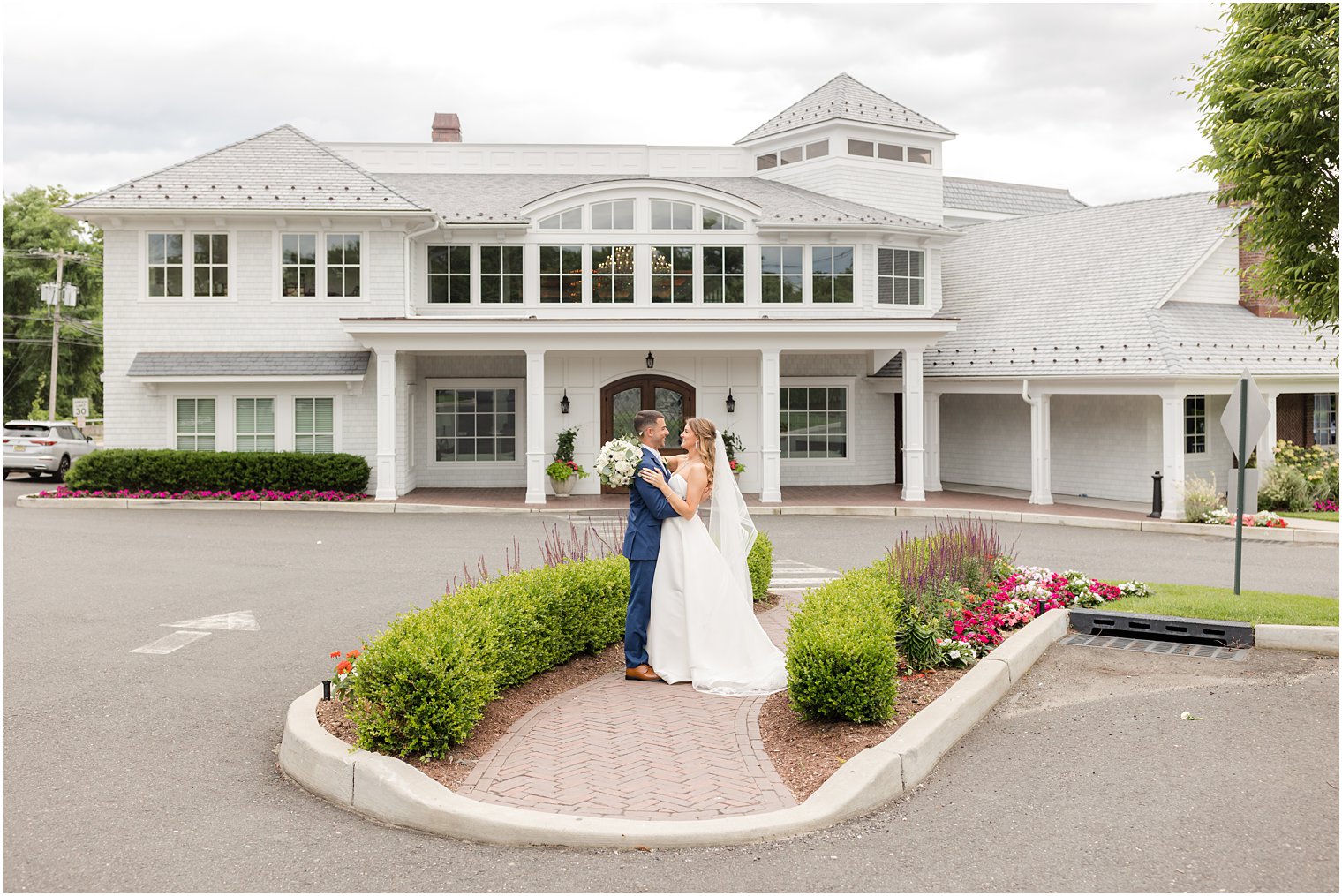 newlyweds pose in garden out front of The Mill Lakeside Manor