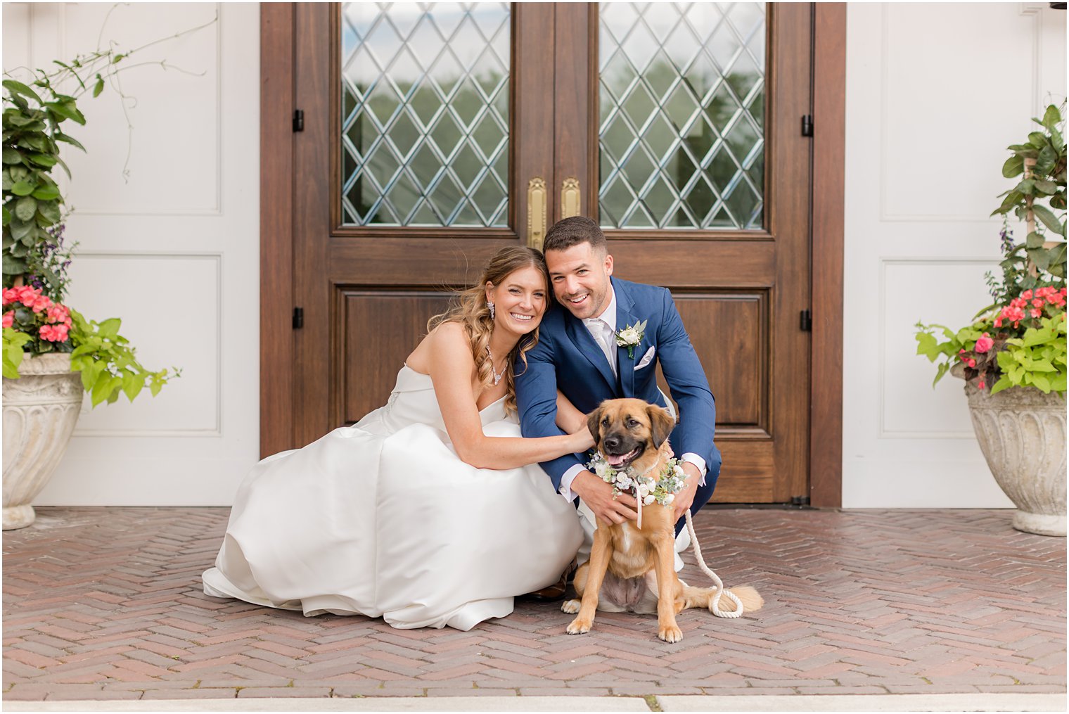 bride and groom pose with dog outside wooden door at The Mill Lakeside Manor