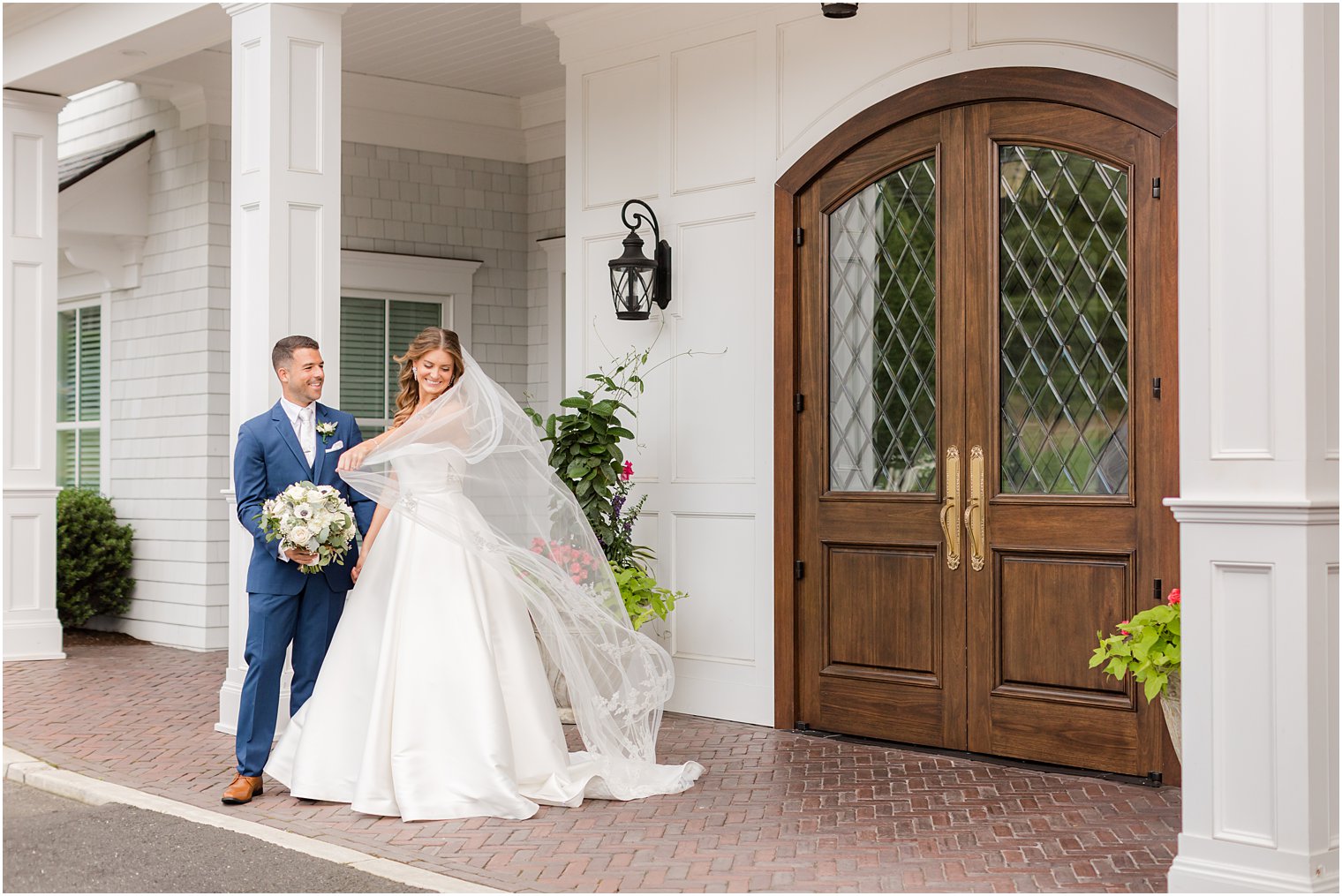 bride holds veil pulling it around her and groom outside The Mill Lakeside Manor