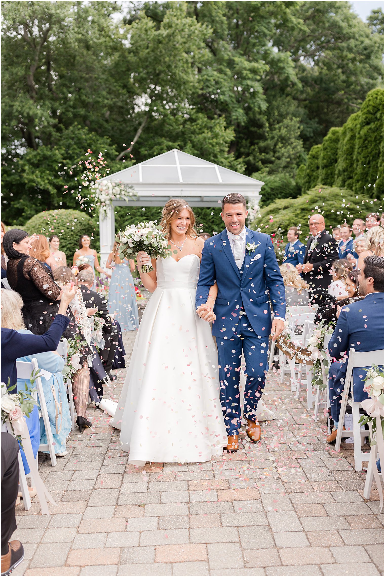 bride and groom walk up aisle through confetti poppers