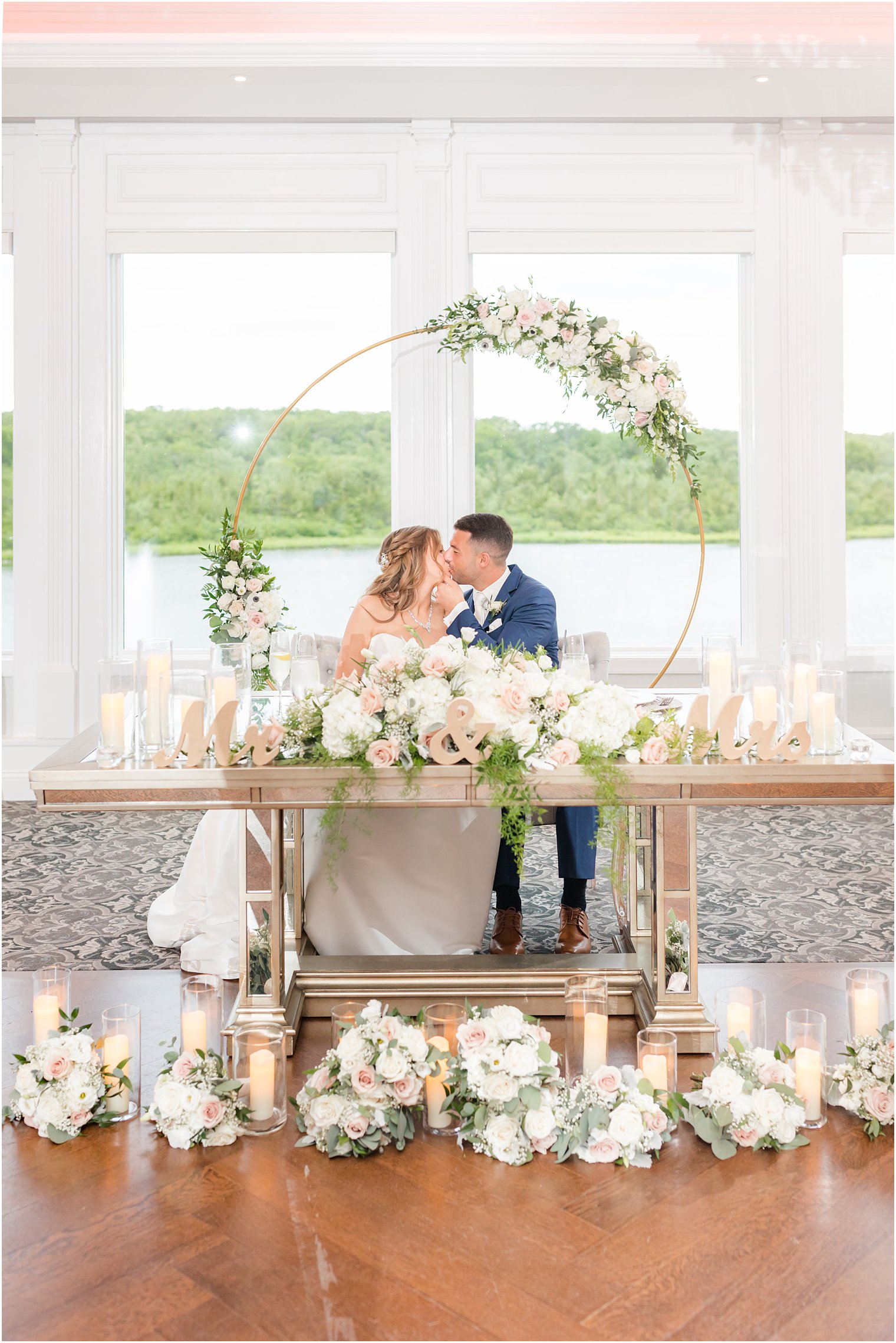 bride and groom kiss at sweetheart table at The Mill Lakeside Manor