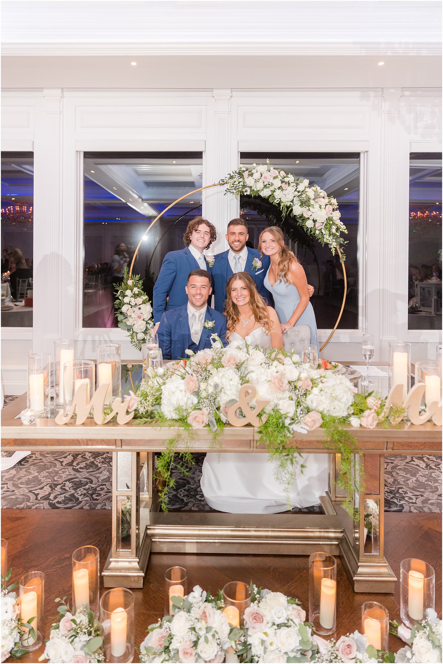 bride and groom sit posing with bridesmaid and groomsmen