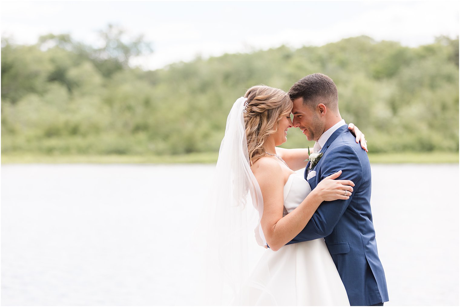 bride and groom lean heads together on dock at The Mill Lakeside Manor